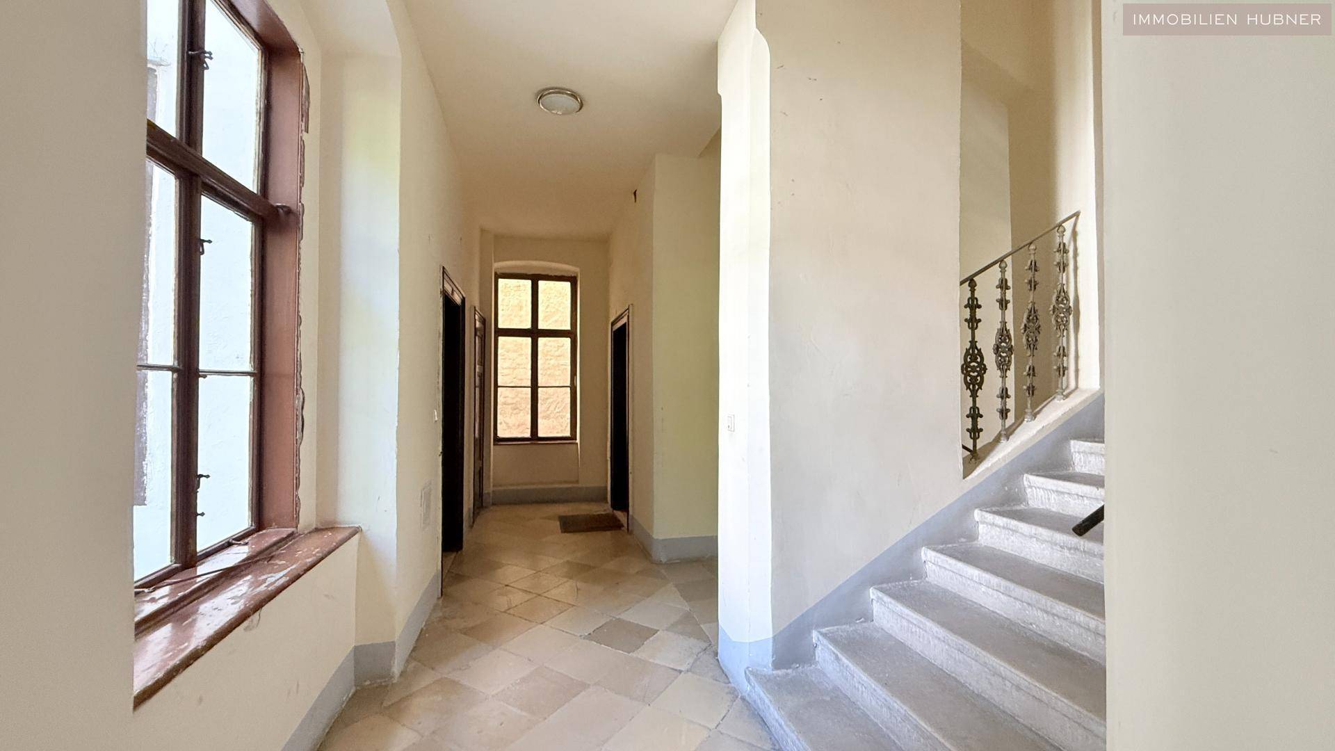 Geräumiger Flur mit Fliesenboden und Zugang zum Treppenhaus in einem Altbau.