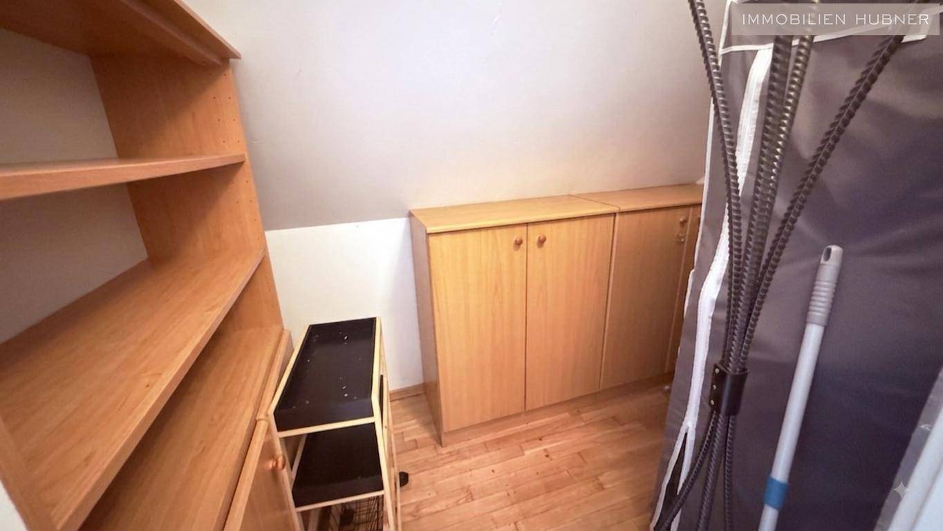 Geräumiger Abstellraum mit Holzregalen und Schränken unter der Dachschräge für zusätzlichen Stauraum.