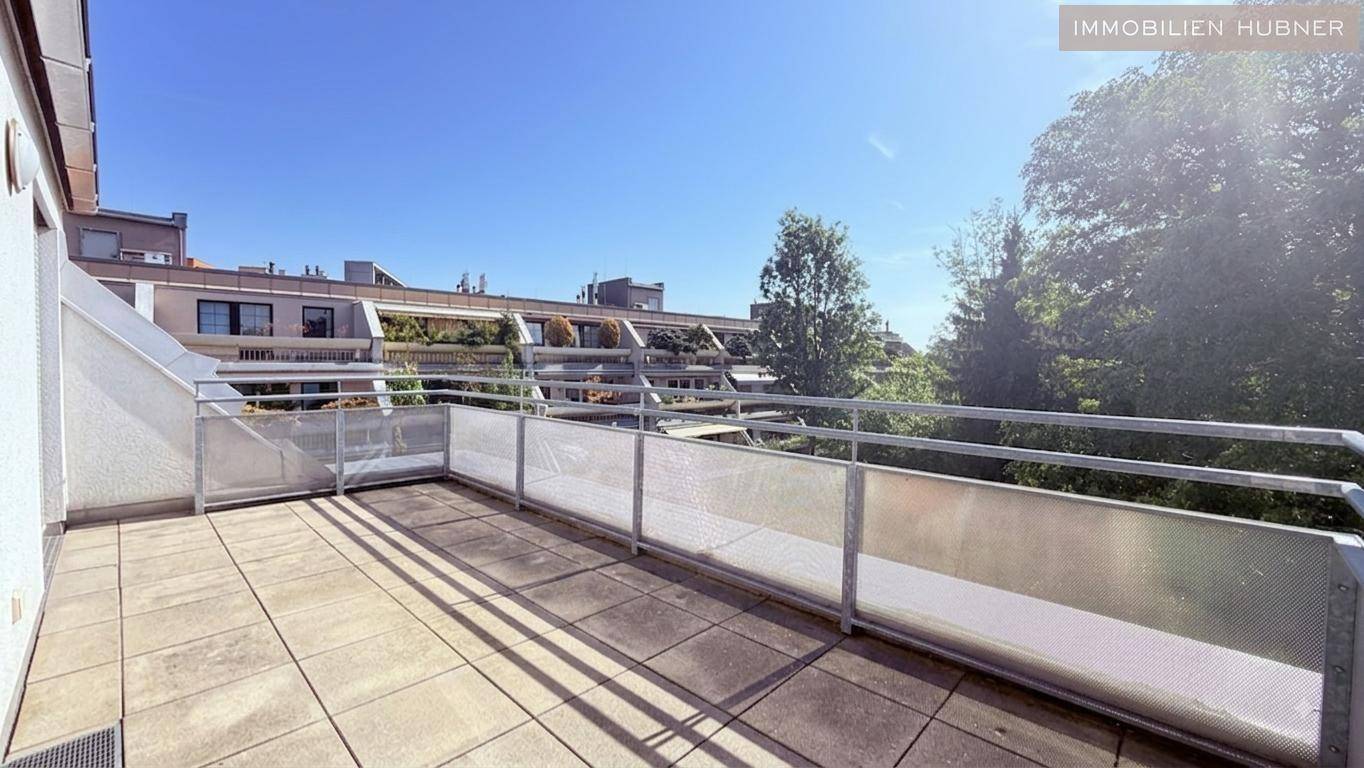 Geräumiger Balkon mit Fliesenboden und Metallgeländer, bietet einen Blick auf die umliegenden Gebäude.