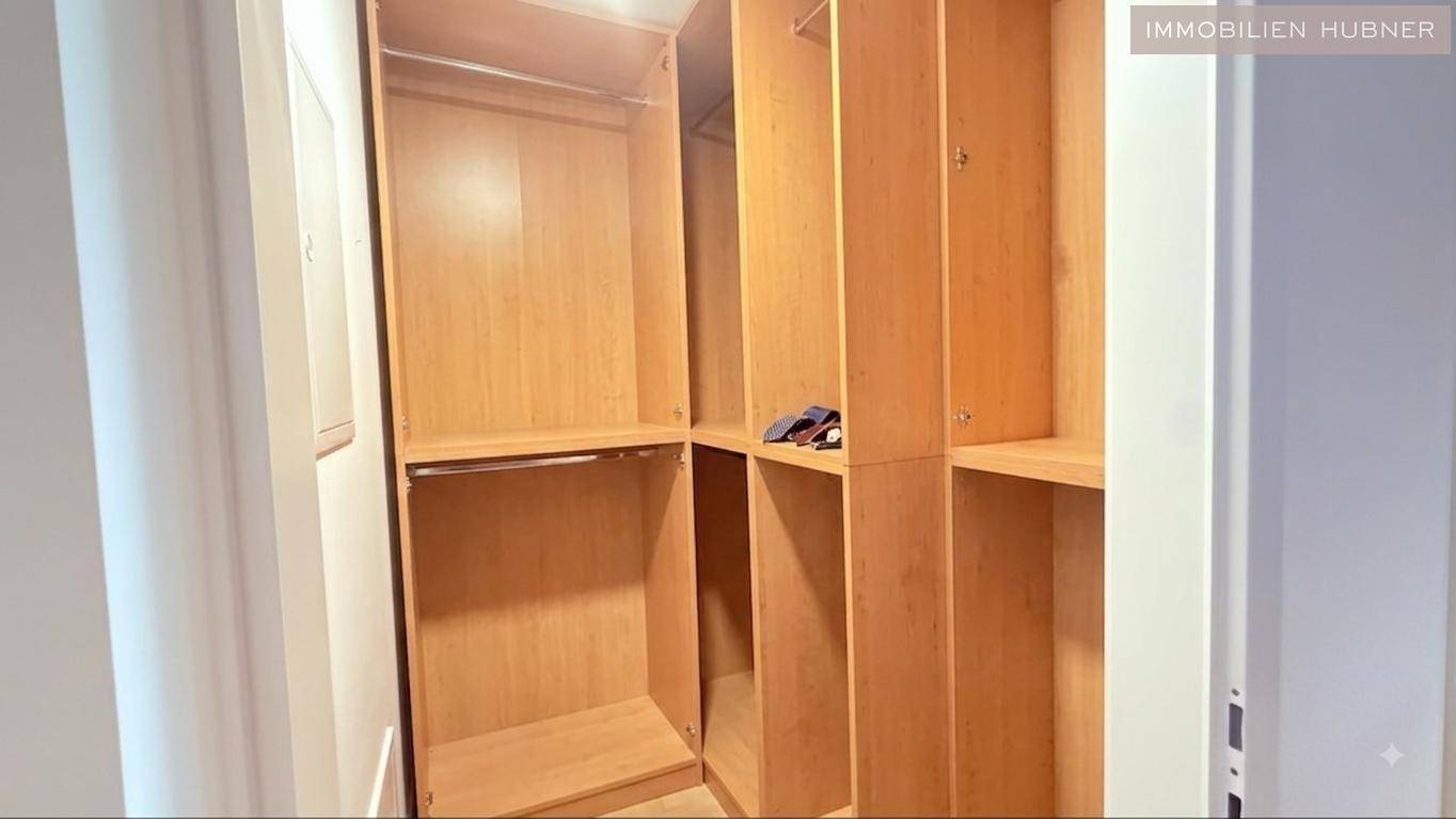 Praktischer begehbarer Kleiderschrank mit viel Stauraum und Holzregalen für Kleidung und Accessoires.