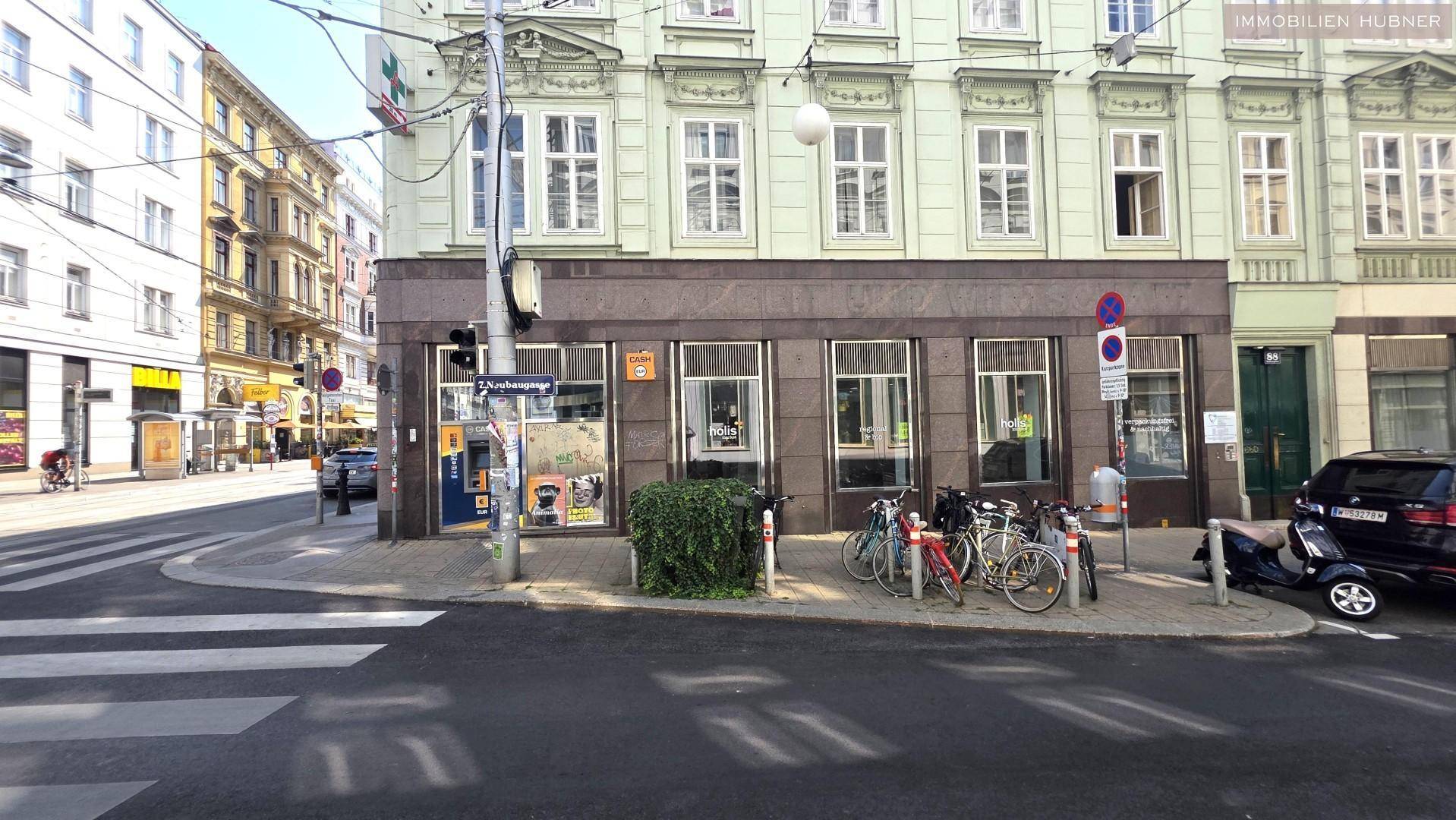 Eine Straßenszene mit einem Geschäftsgebäude, Fahrrädern und einem Zebrastreifen.