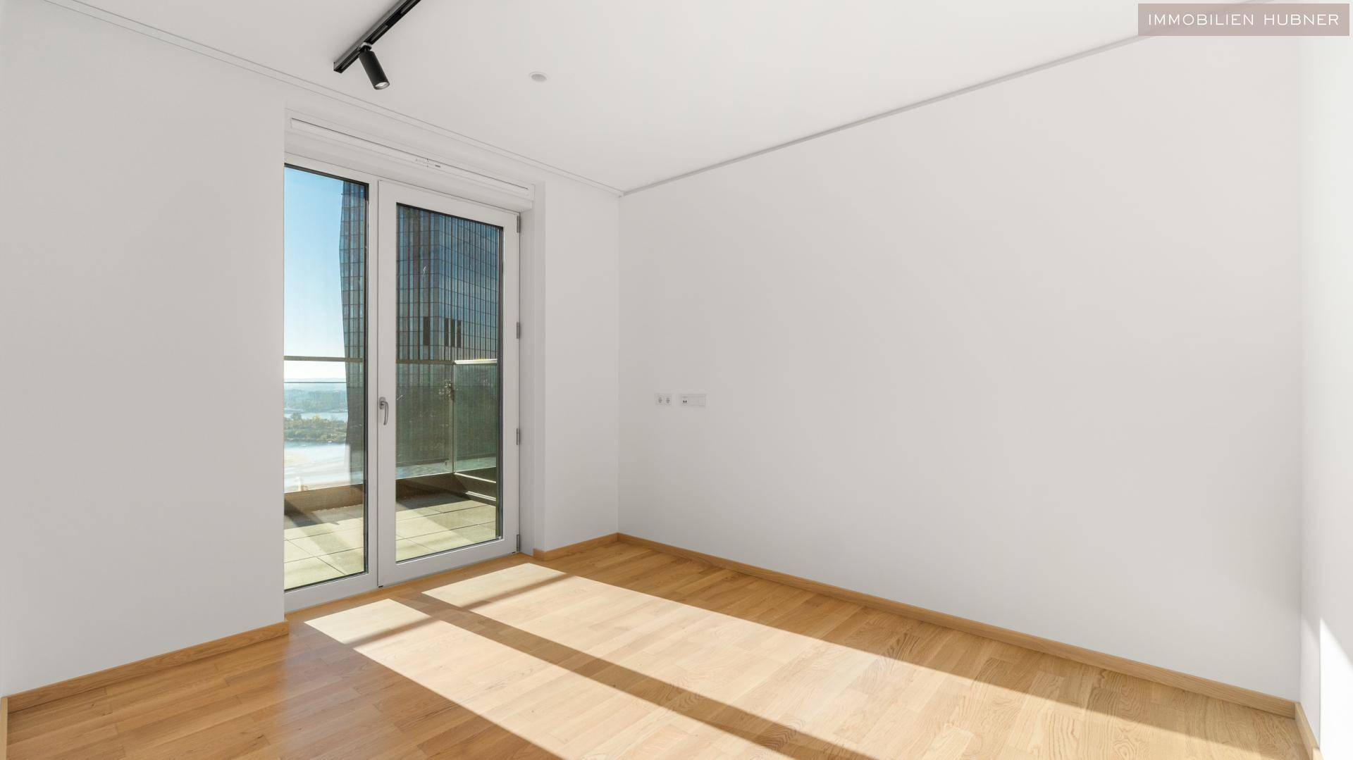 Helles Zimmer mit Parkettboden und Zugang zu einem Balkon, ideal als Schlaf- oder Arbeitszimmer.