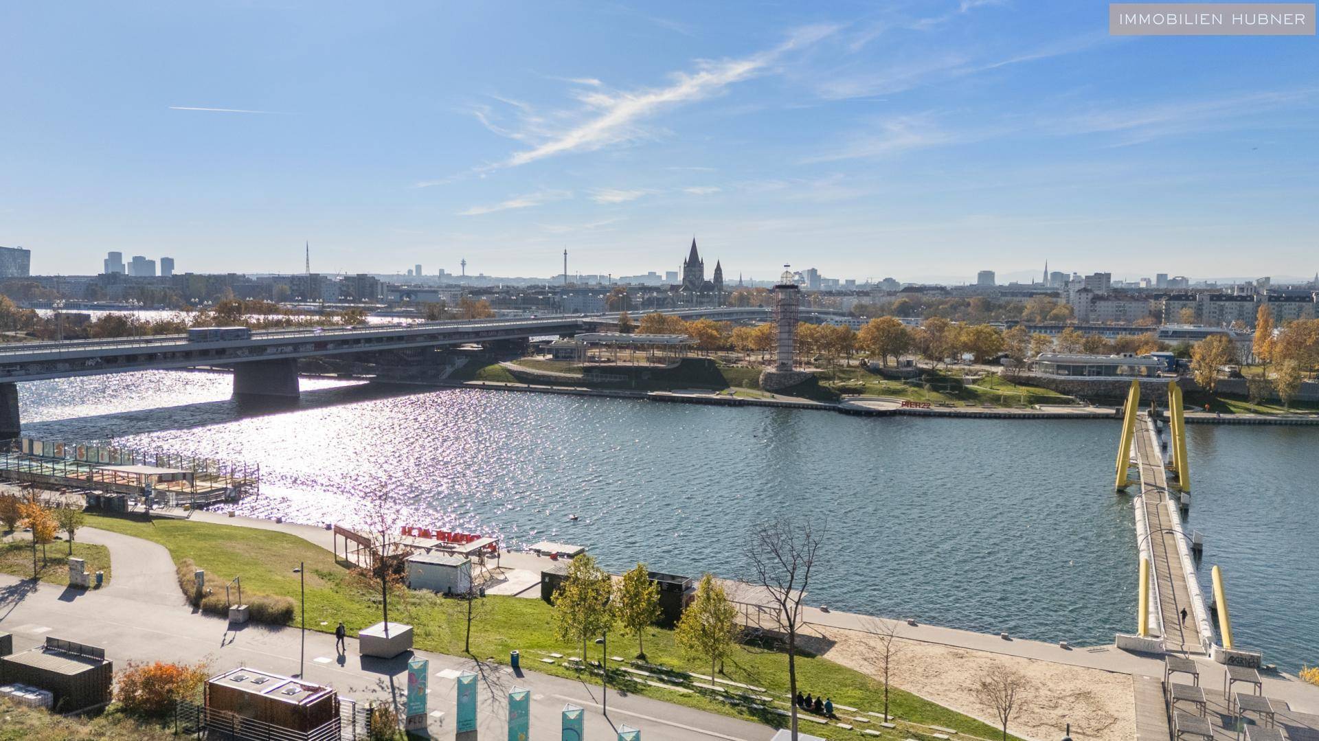 Weitläufiger Blick auf den Fluss, Brücken und die Stadtlandschaft unter blauem Himmel.