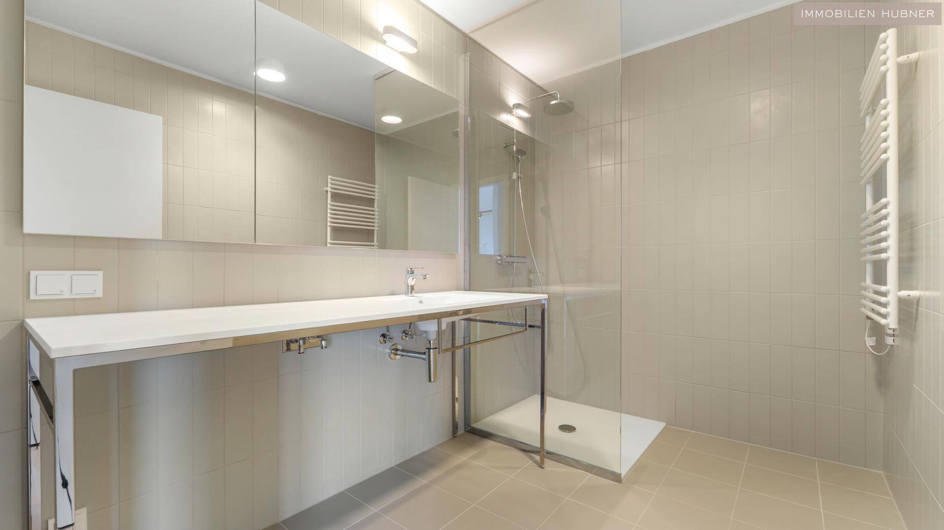 Modernes Badezimmer mit großer begehbarer Dusche, Einzelwaschbecken und beheiztem Handtuchhalter.