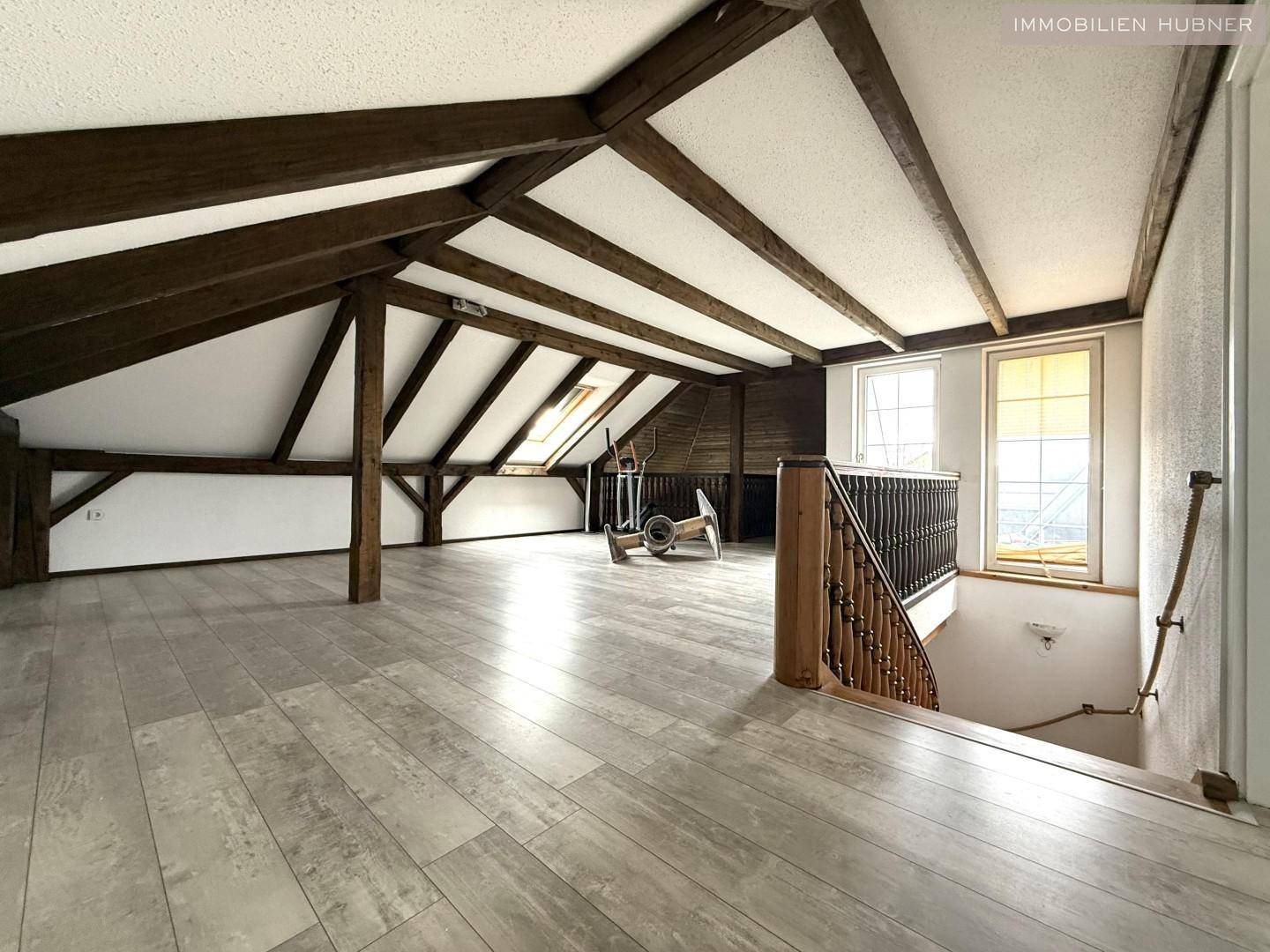 Ausgebauter Dachboden mit Holzbalken, Laminatboden und Dachfenstern.