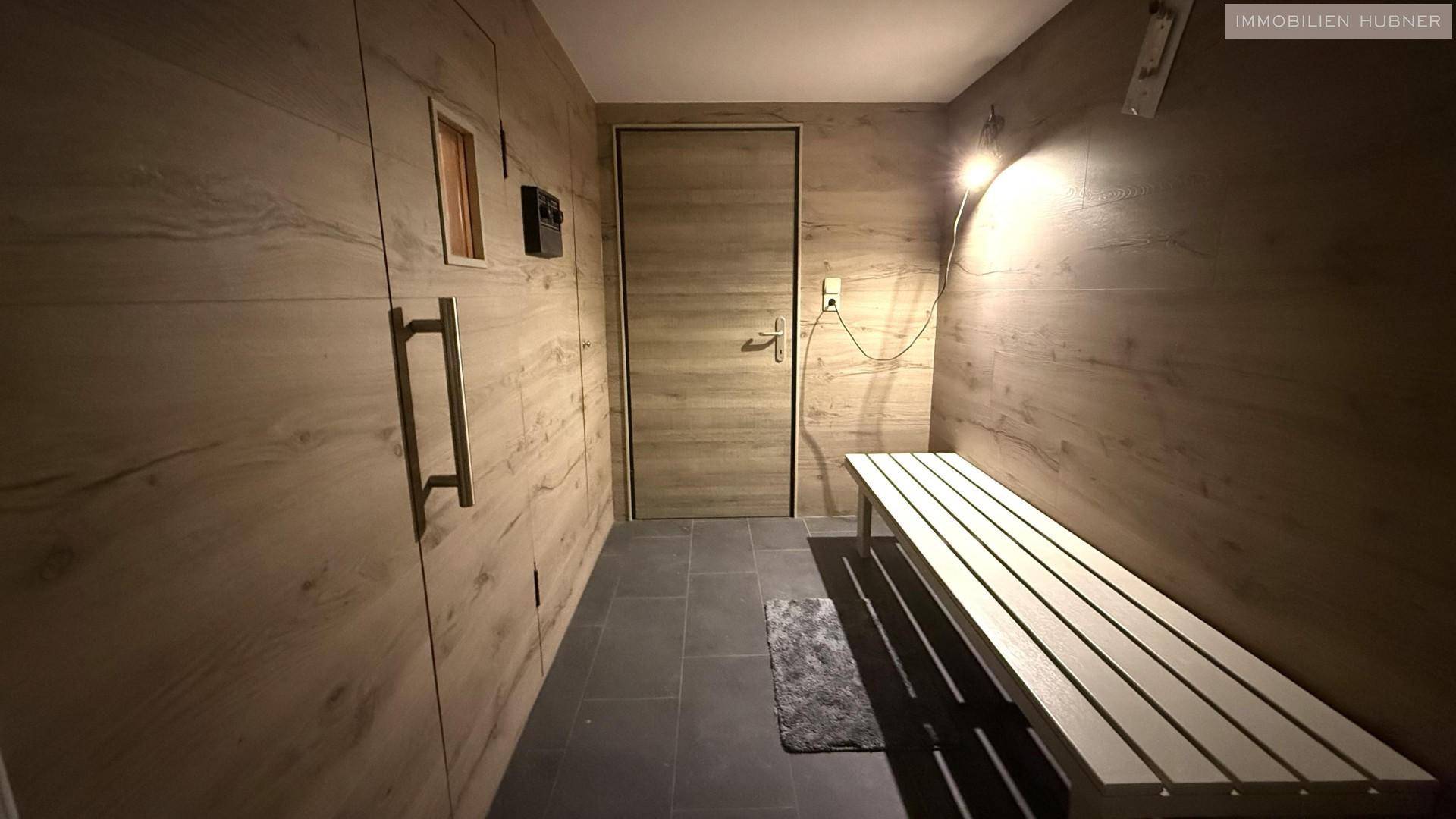 Flur im Wellnessbereich mit Holzwänden und einer Sitzbank, führt zur Sauna.