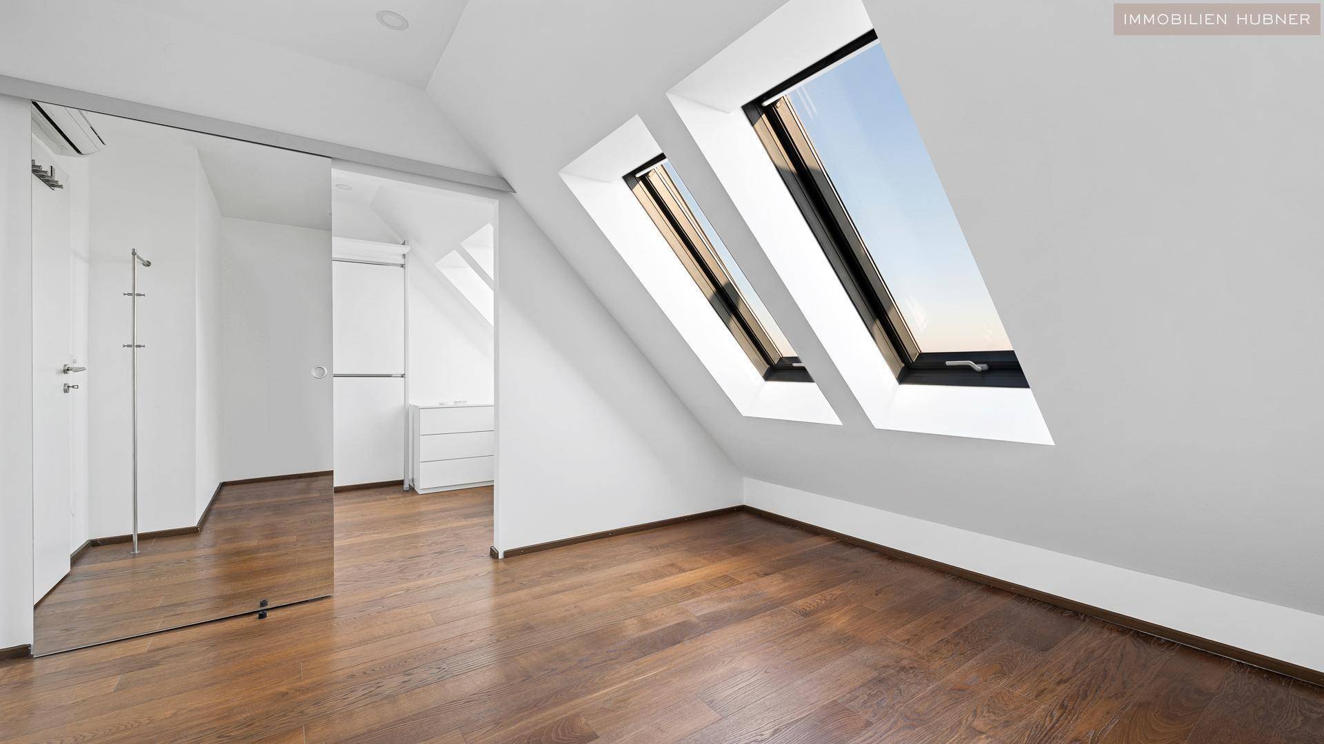 Schlafzimmer mit Holzboden, Dachschrägen und zwei großen Dachfenstern für viel Licht.