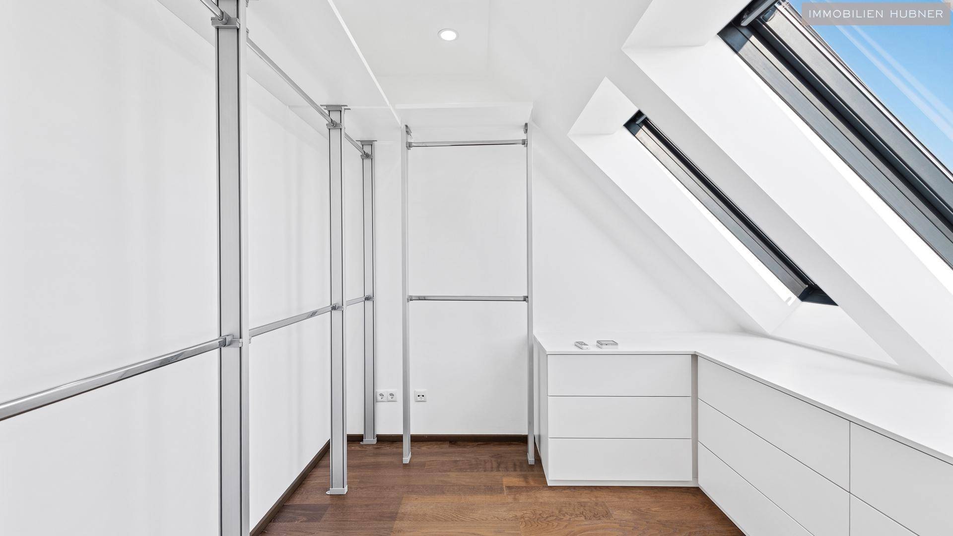Begehbarer Kleiderschrank mit offenen Regalsystemen und Dachfenstern in einem hellen Raum.