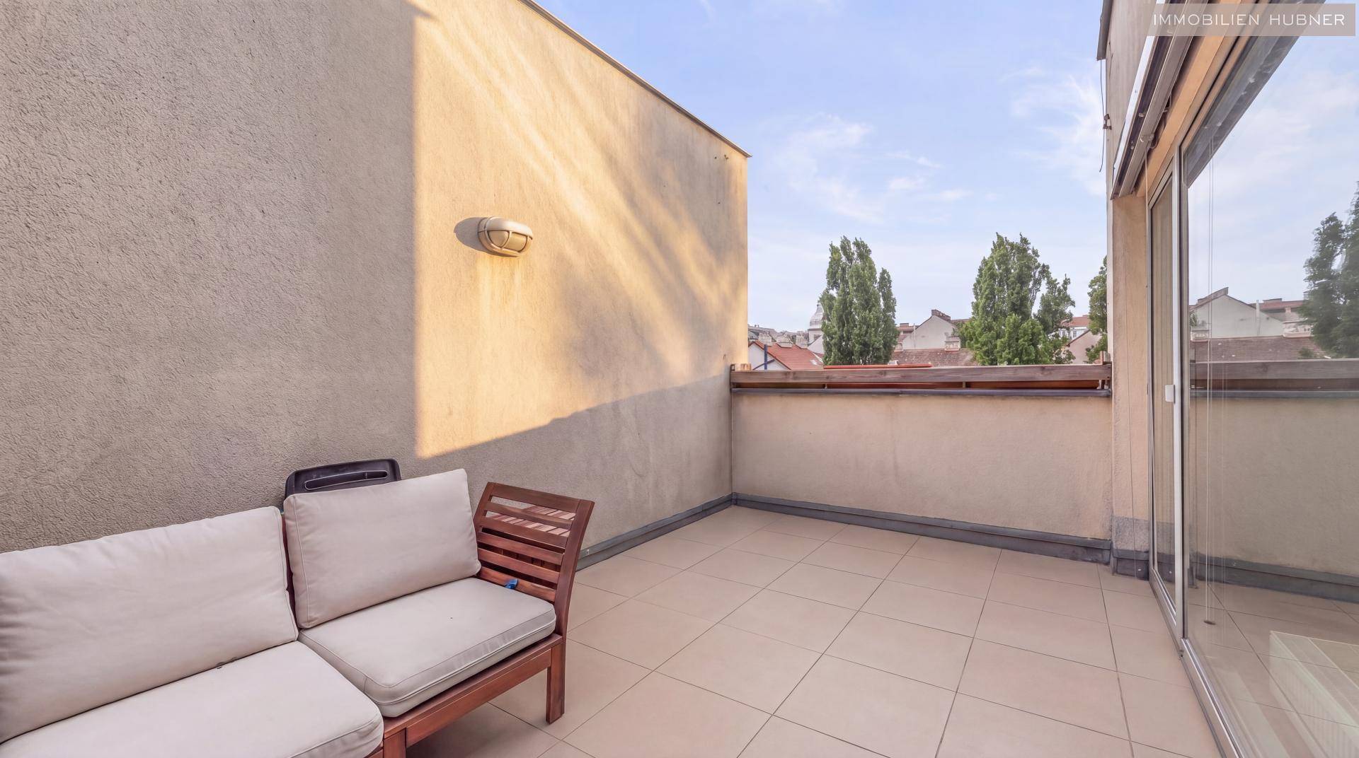 Geräumige Terrasse mit Fliesenboden und bequemen Outdoor-Sitzmöbeln, ideal zum Entspannen.