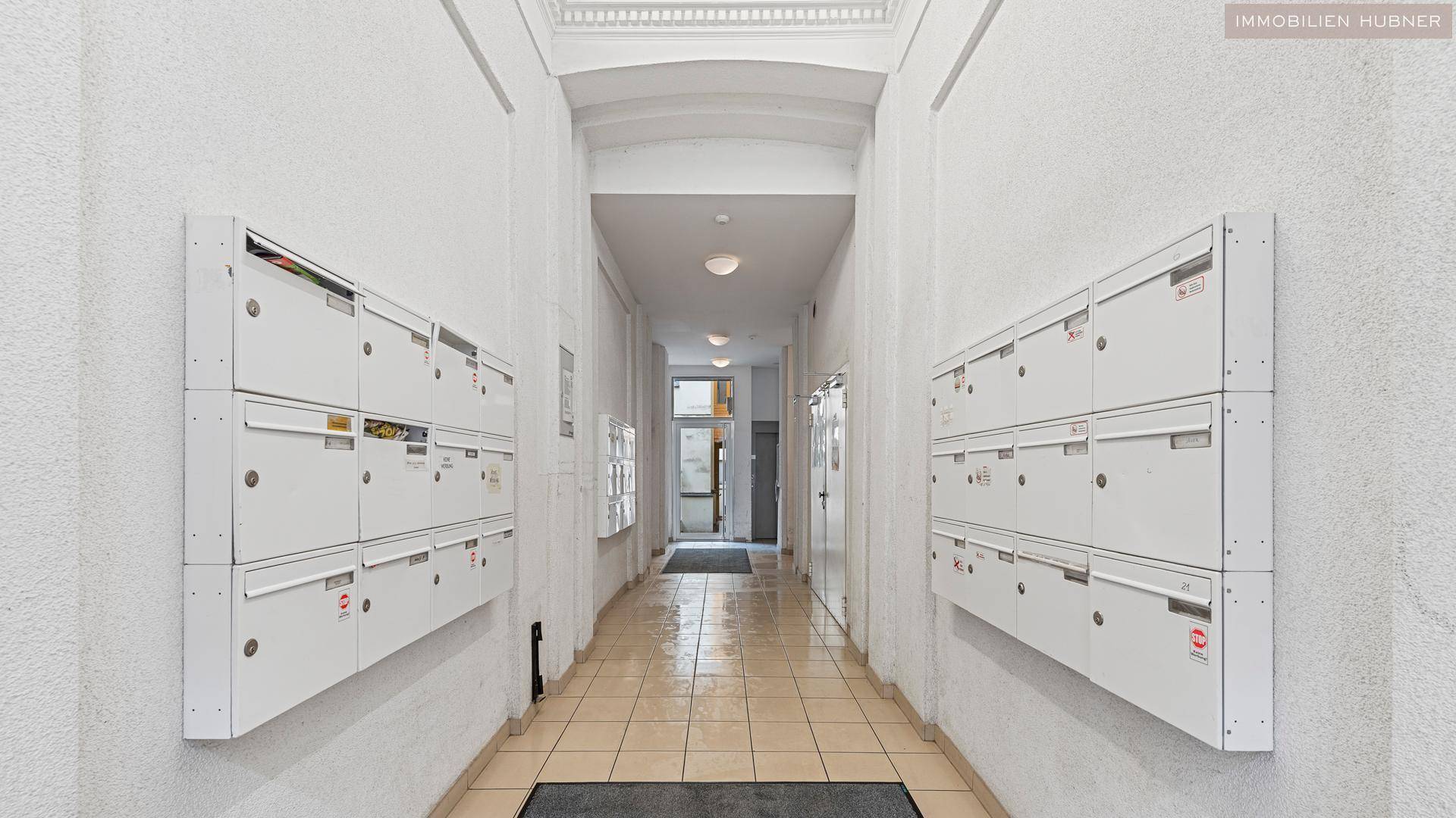 Eingangsbereich des Gebäudes mit Reihen von Briefkästen an beiden Wänden und Fliesenboden.