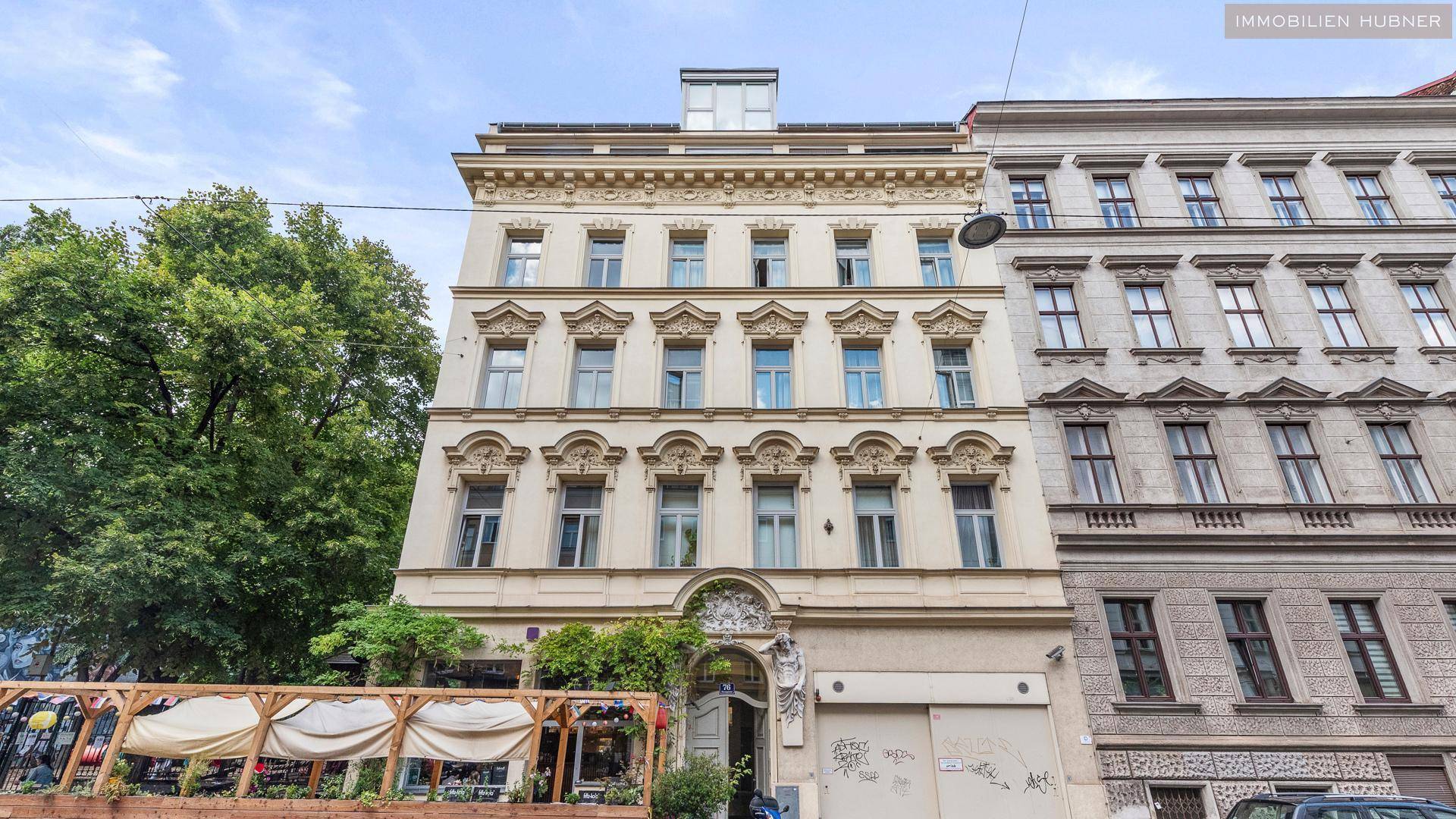 Historische Gebäudefassade mit reich verzierten Details, vielen Fenstern und einem Restaurant im Erdgeschoss.