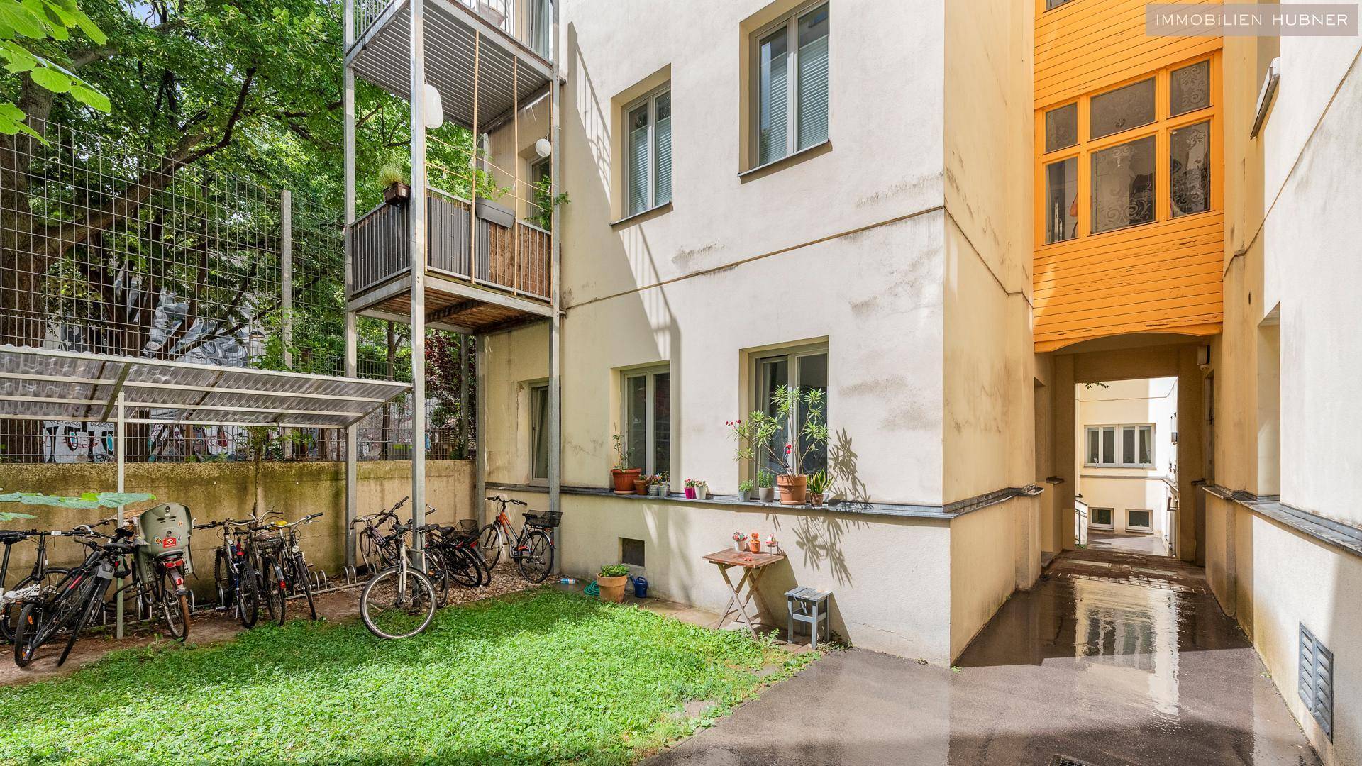 Hinterhof des Gebäudes mit Rasenfläche, Fahrradabstellplatz und externen Metalltreppen zu Balkonen.