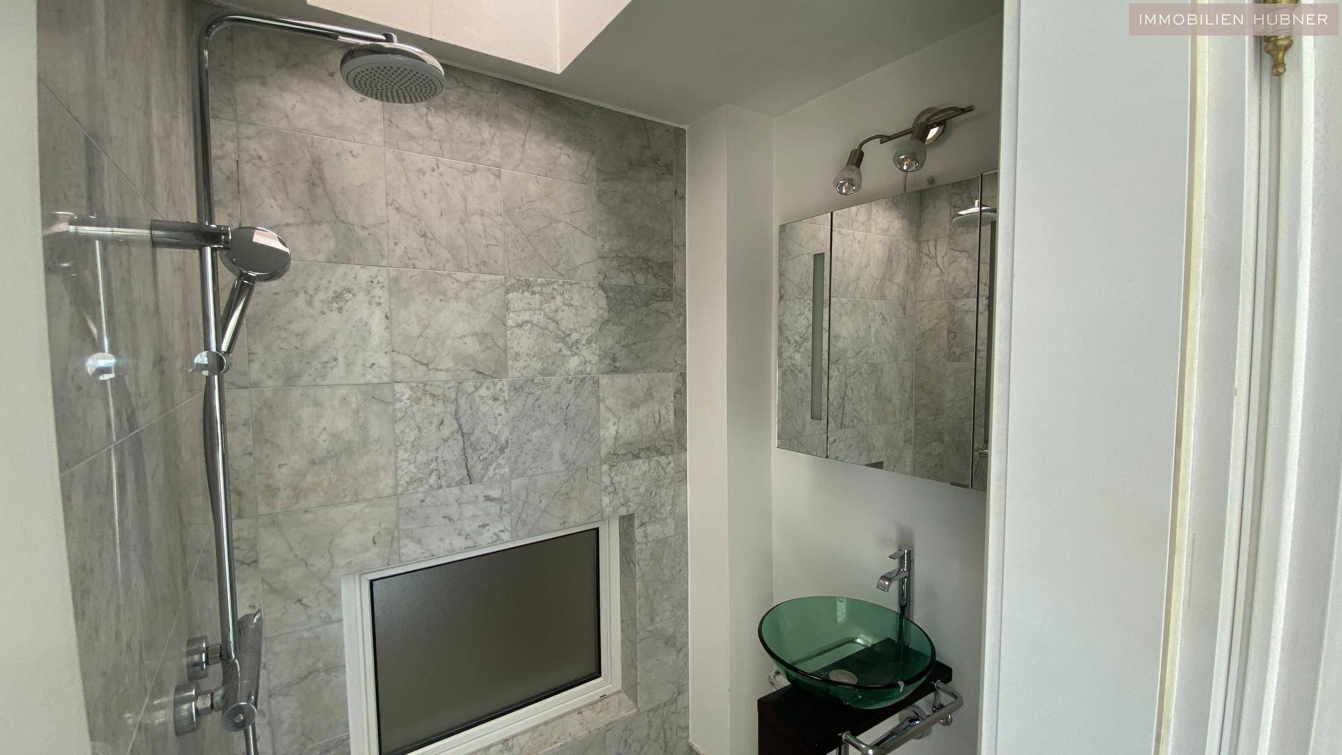 Modernes Badezimmer mit begehbarer Dusche, Glaswaschbecken und Marmoroptik-Fliesen.