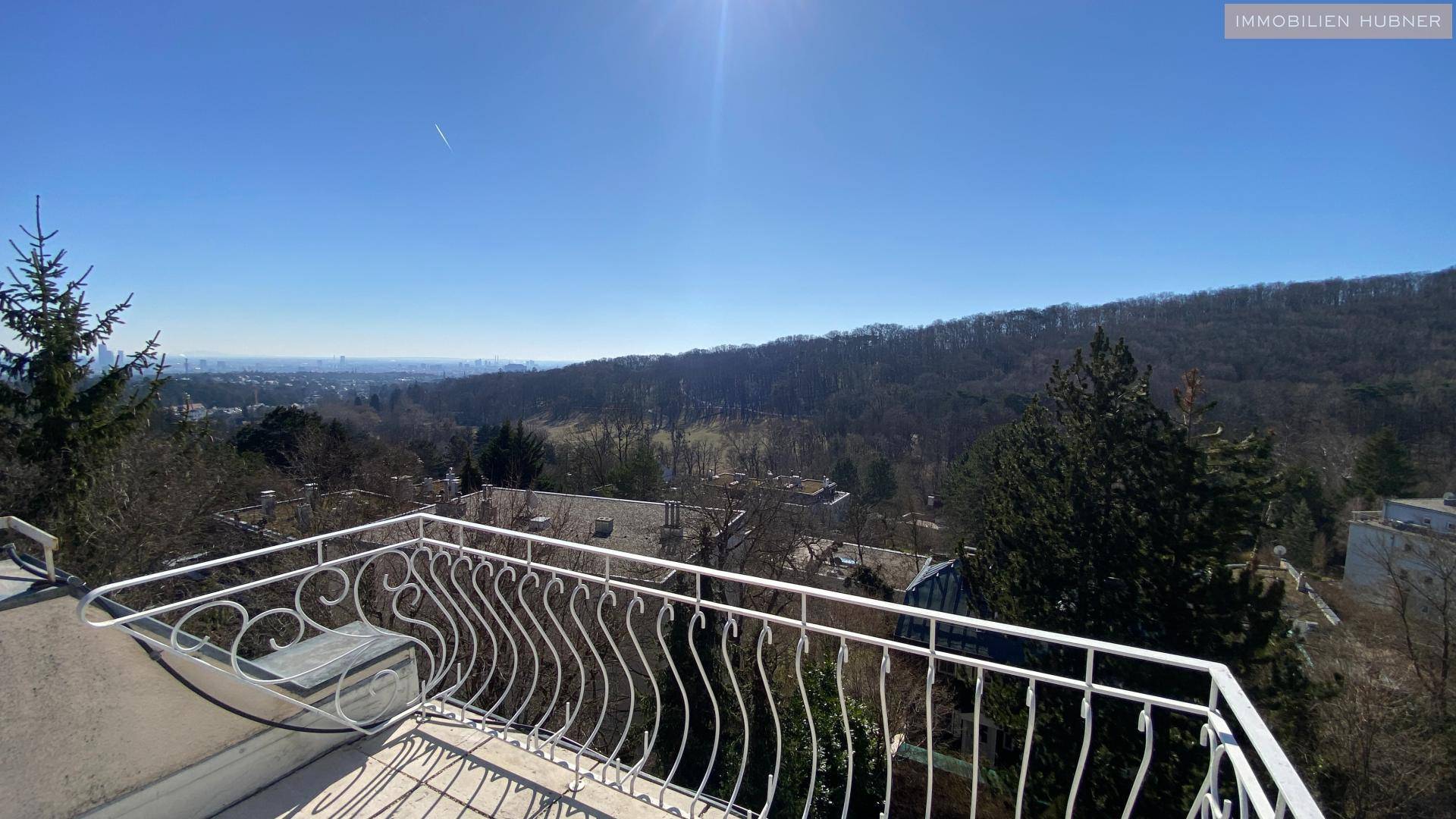 Panoramablick vom Balkon über grüne Hügel und die Stadt in der Ferne unter blauem Himmel.