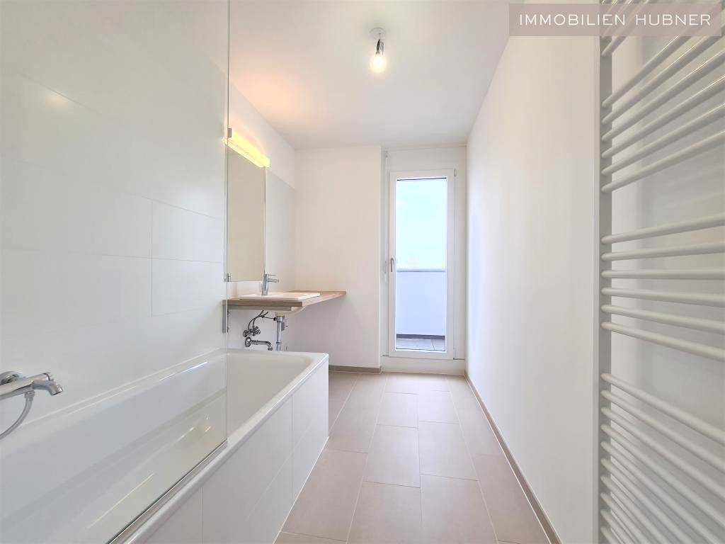 Modernes Badezimmer mit Badewanne, Einzelwaschbecken und beheiztem Handtuchhalter.