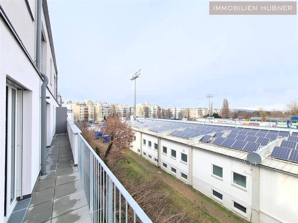 Langer Balkon mit Metallgeländer und Blick auf Gebäude mit Solaranlagen und die Stadt.