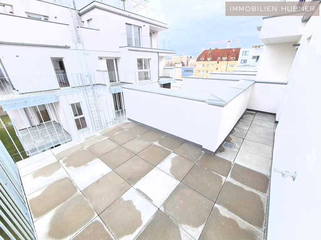 Große geflieste Terrasse mit Blick auf die umliegenden Gebäude und den Himmel.