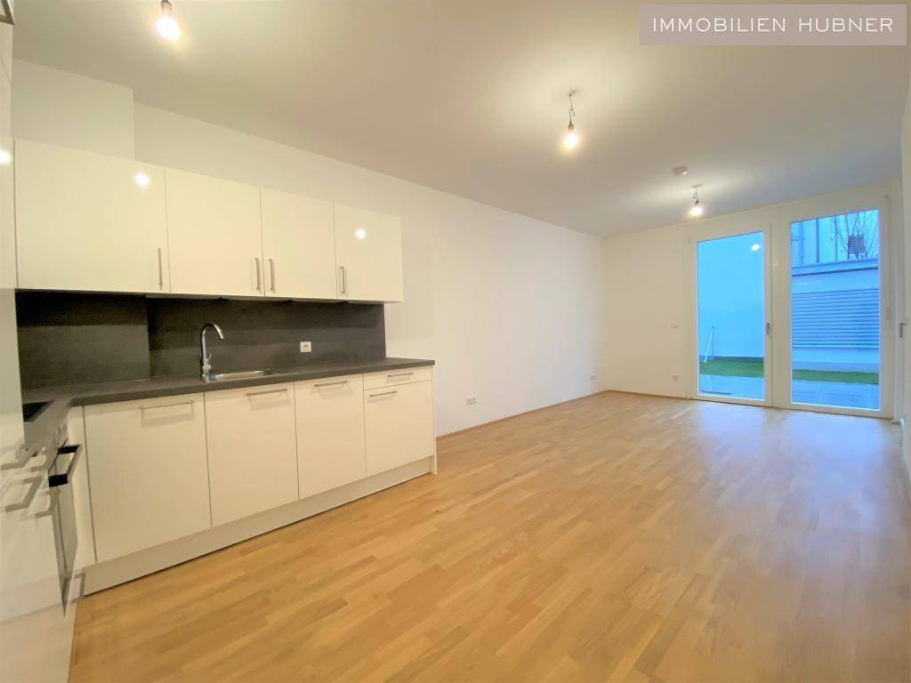 Heller Wohnbereich mit integrierter Küchenzeile, Holzfußboden und Zugang zum Garten.
