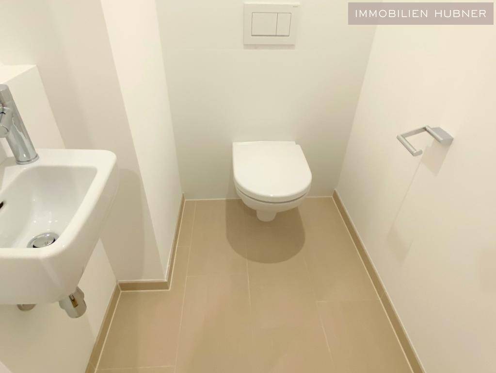 Separates WC mit wandhängendem WC und kleinem Waschbecken.