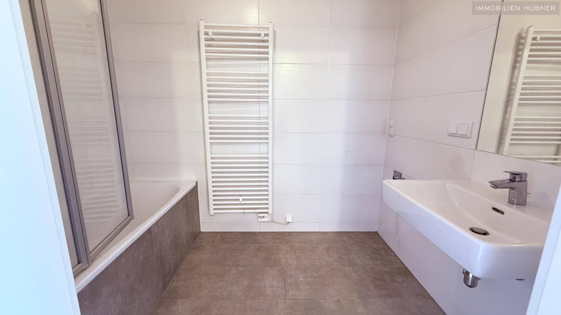 Modernes Badezimmer mit Badewanne, Waschtisch und beheiztem Handtuchhalter.