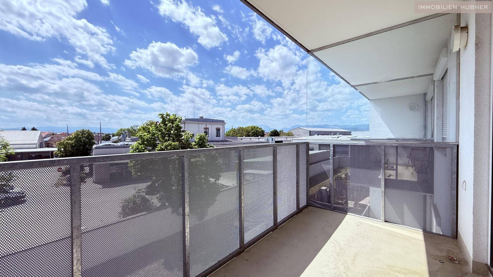 Heller Balkon mit weitem Blick über die Nachbarschaft und den blauen Himmel.