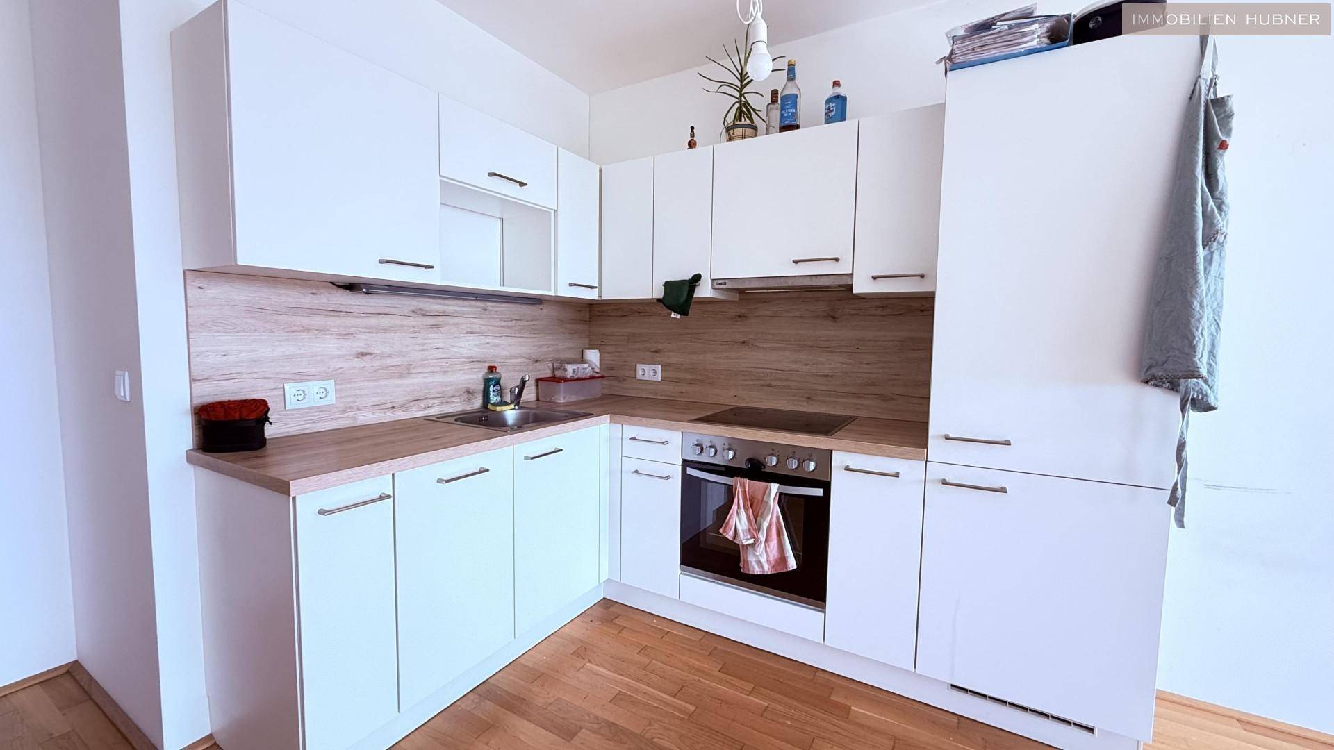 Moderne Einbauküche mit weißen Schränken, Holzoptik-Arbeitsplatte und integriertem Backofen.