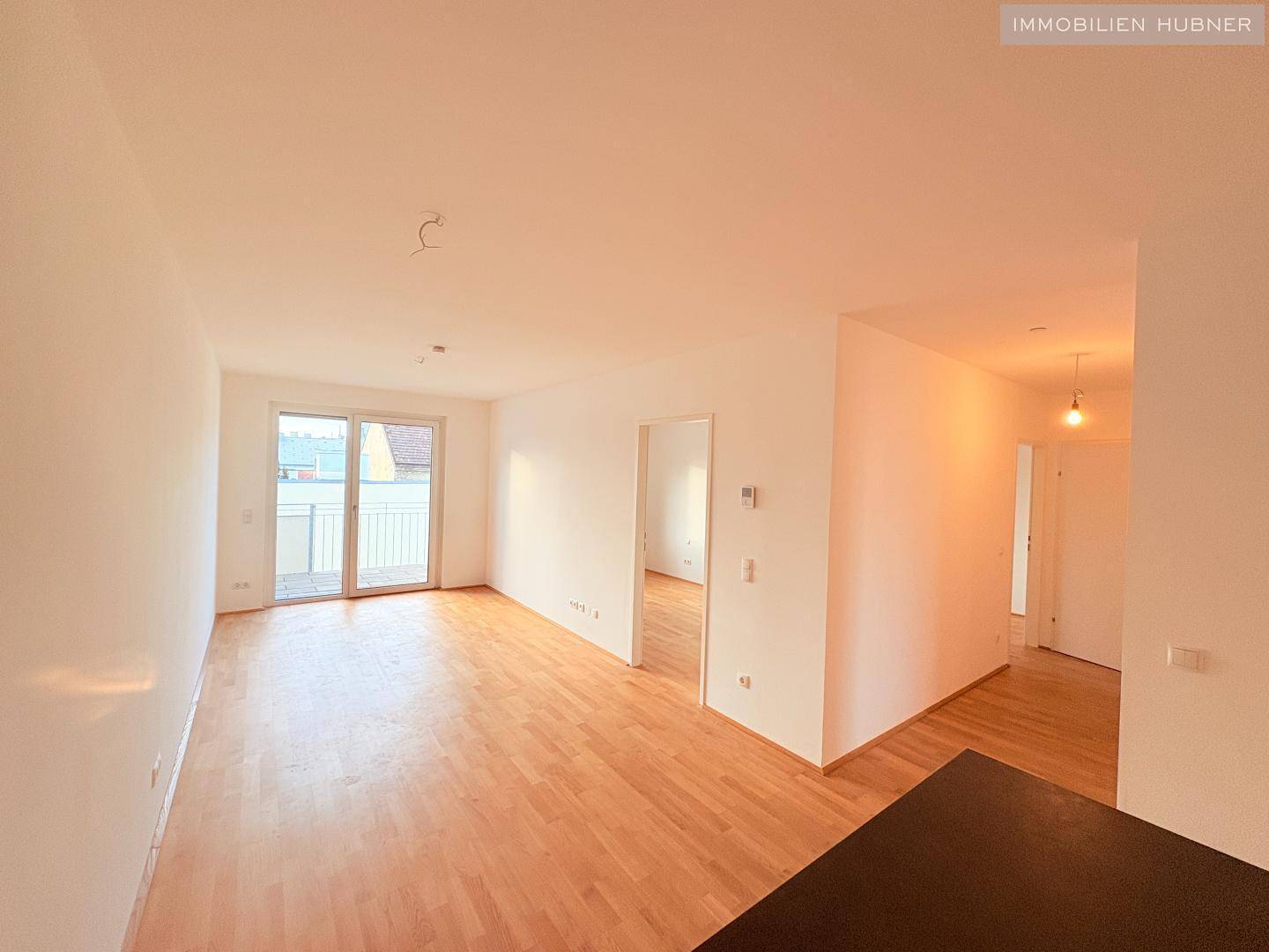 Geräumiges Zimmer mit hellem Parkettboden und Zugang zu einem Balkon, ideal für einen Wohnbereich.