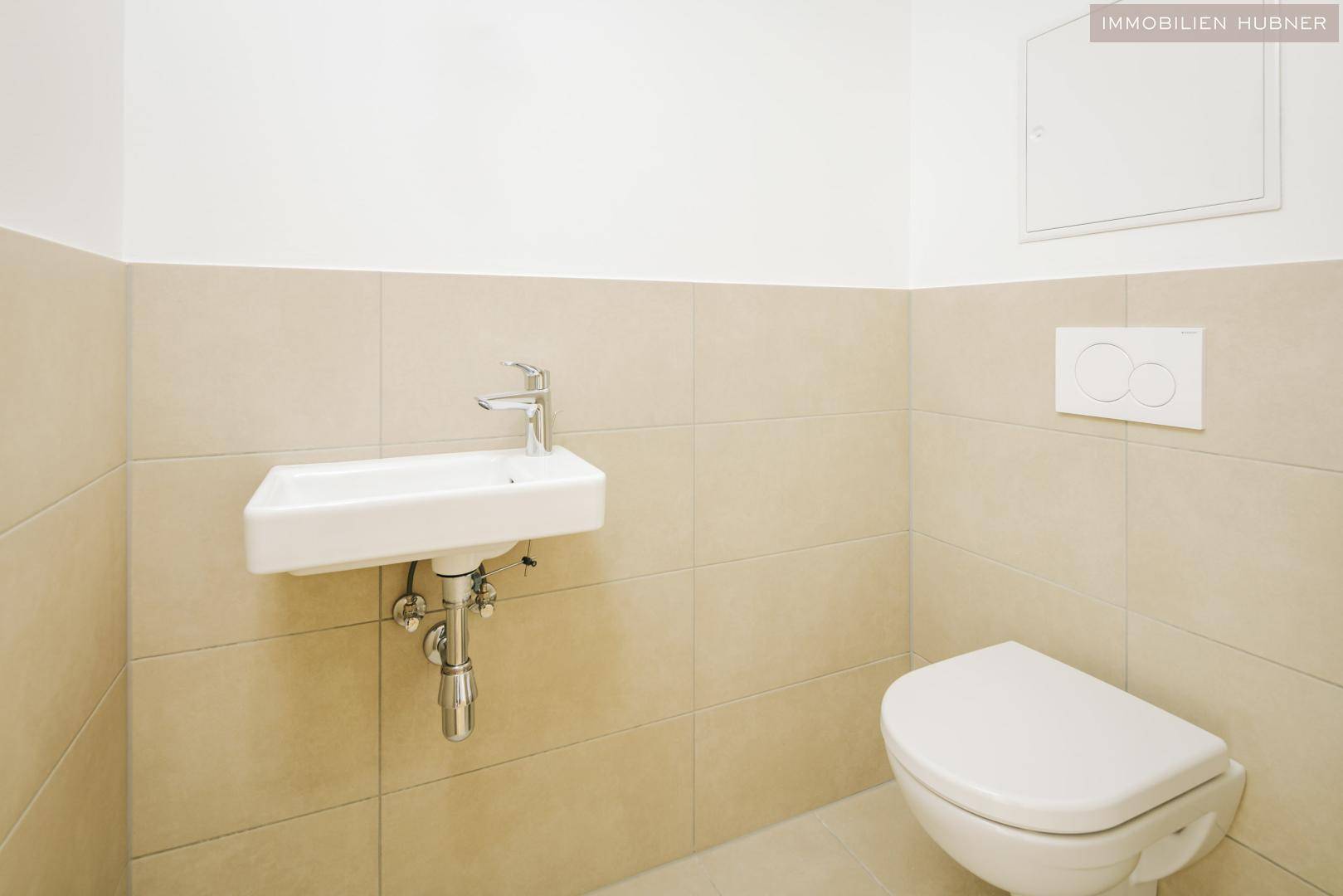 Modernes Gäste-WC mit beigefarbenen Fliesen, wandhängendem WC und kleinem Waschbecken.