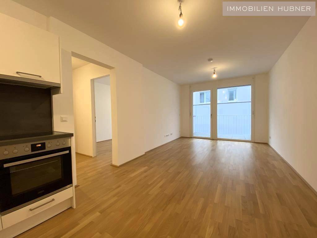 Geräumiger Wohnbereich mit hellem Parkettboden und Zugang zu einem Balkon, ideal für individuelle Gestaltung.