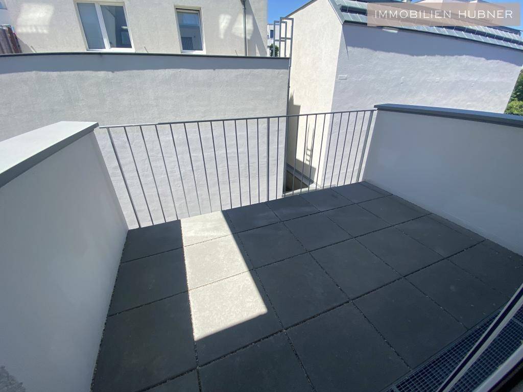 Heller Balkon mit grauen Fliesen und Metallgeländer, bietet einen privaten Außenbereich.