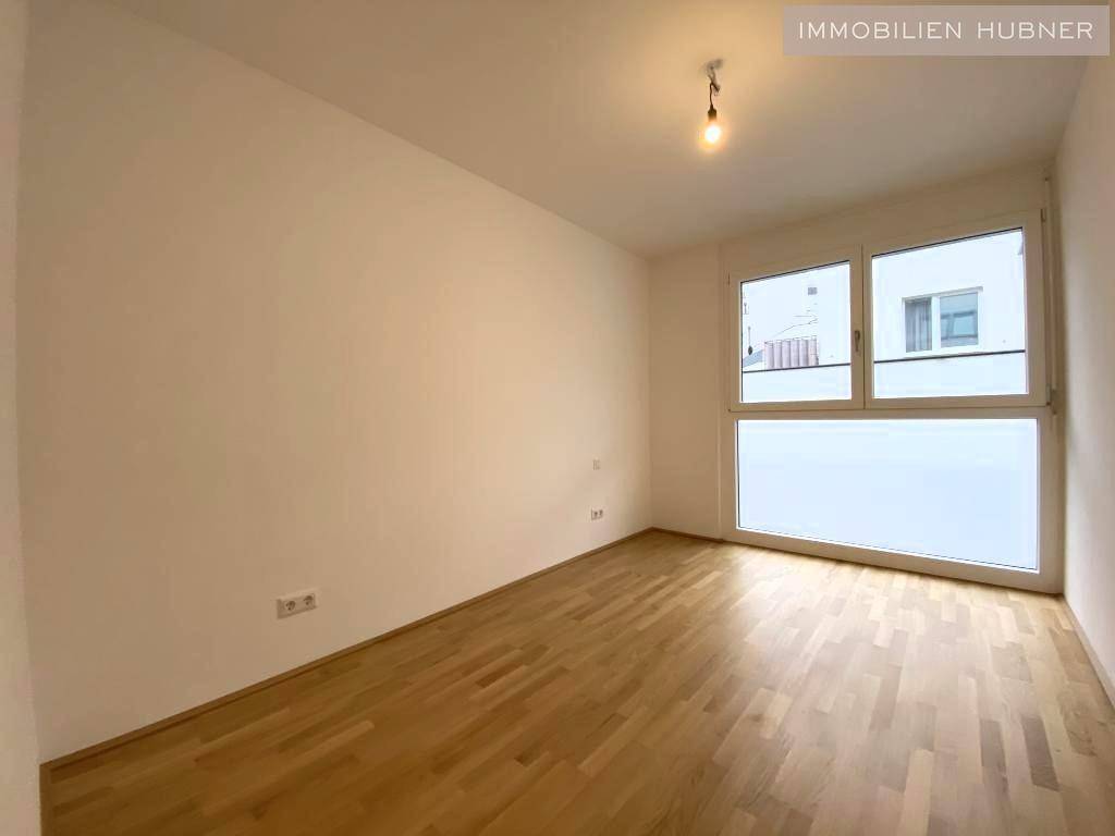 Helles Zimmer mit Parkettboden und großem Fenster, vielseitig nutzbar als Schlaf- oder Arbeitszimmer.