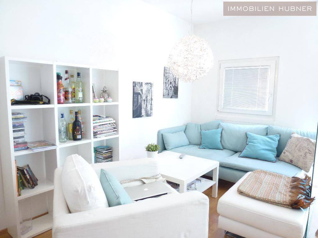 Gemütliches Wohnzimmer mit hellblauer Couch, weißem Regal und moderner Deckenleuchte.