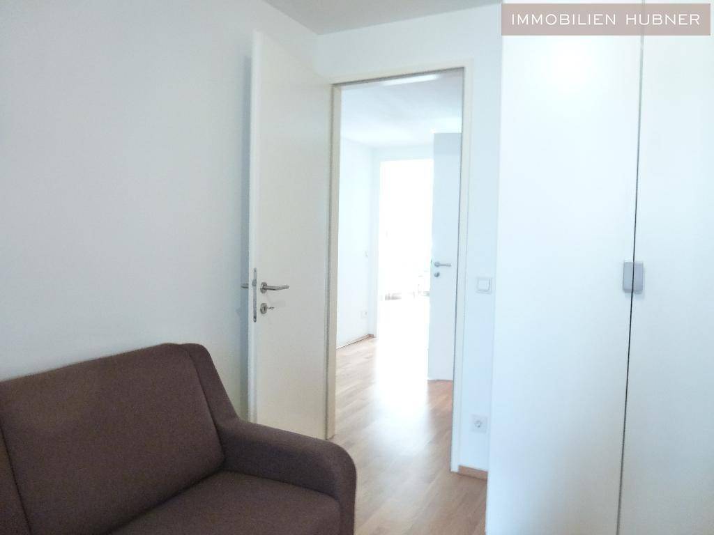 Heller Flur mit Holzboden und weißen Türen, der zu weiteren Räumen führt.