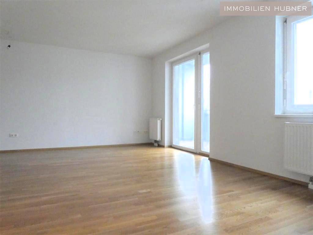 Geräumiges, helles Zimmer mit Parkettboden und Balkonzugang, bietet viel Potenzial für Wohnideen.