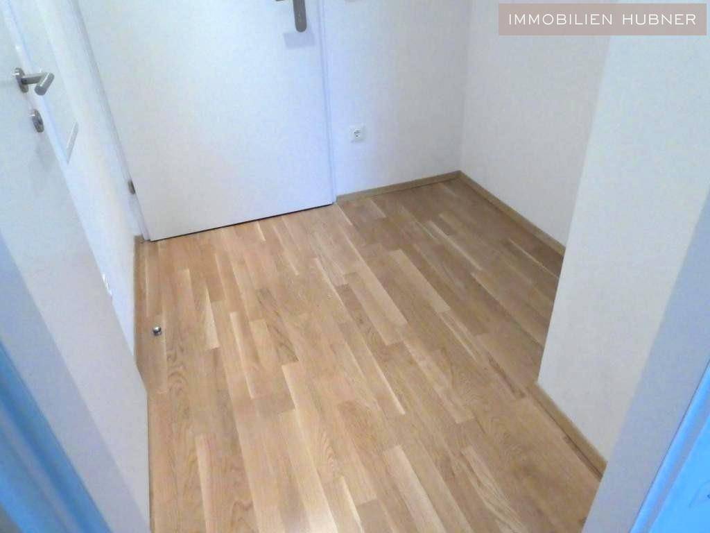 Heller Flur mit Parkettboden und weißen Wänden, der zu den verschiedenen Räumen der Wohnung führt.
