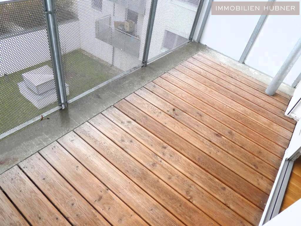 Balkon mit robustem Holzboden und modernem Metallgeländer, bietet einen angenehmen Außenbereich.