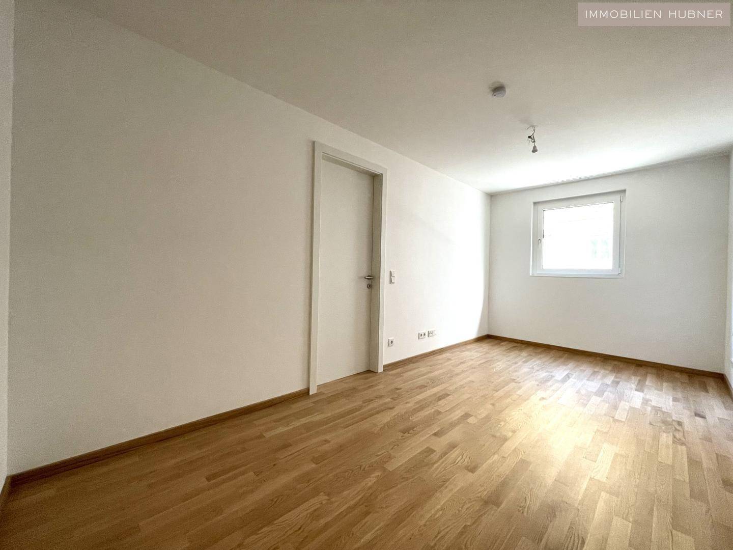 Helles Zimmer mit Parkettboden und einem Fenster, ideal als Schlaf- oder Arbeitszimmer nutzbar.