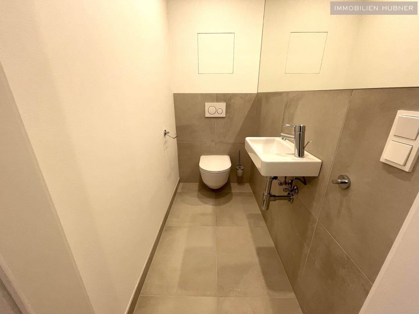Modernes Gäste-WC mit Wand-WC und kleinem Waschbecken in schlichtem Design.