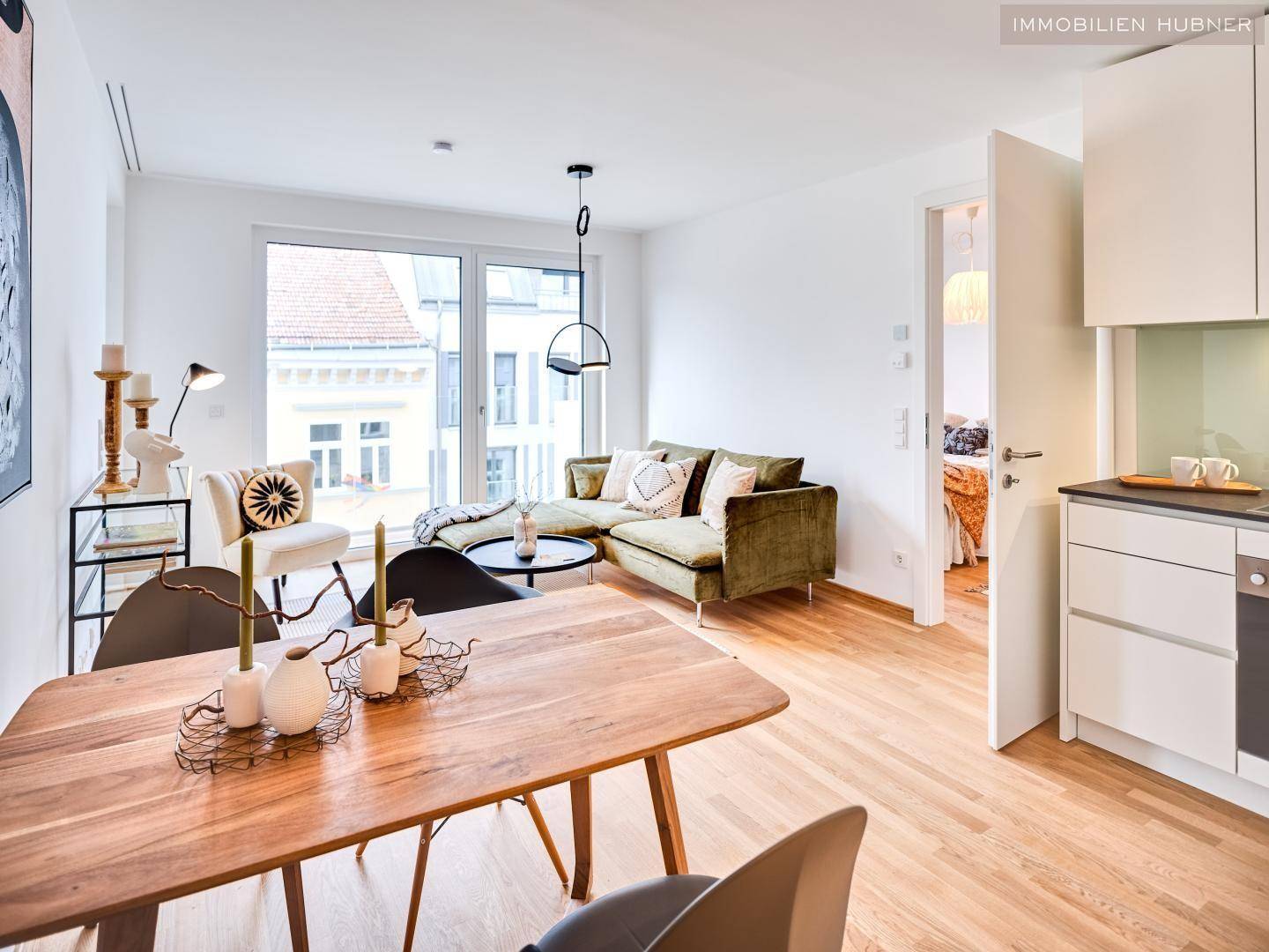Gemütlicher Wohn-Essbereich mit offener Küche, Parkettboden und modernen Möbeln.