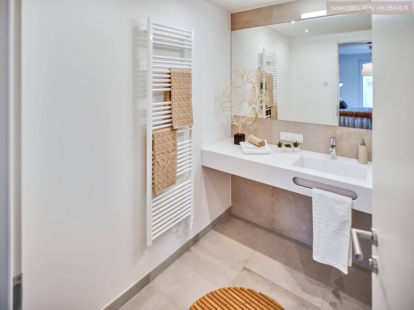 Modernes Badezimmer mit großem Waschtisch, Spiegel und beheiztem Handtuchhalter.