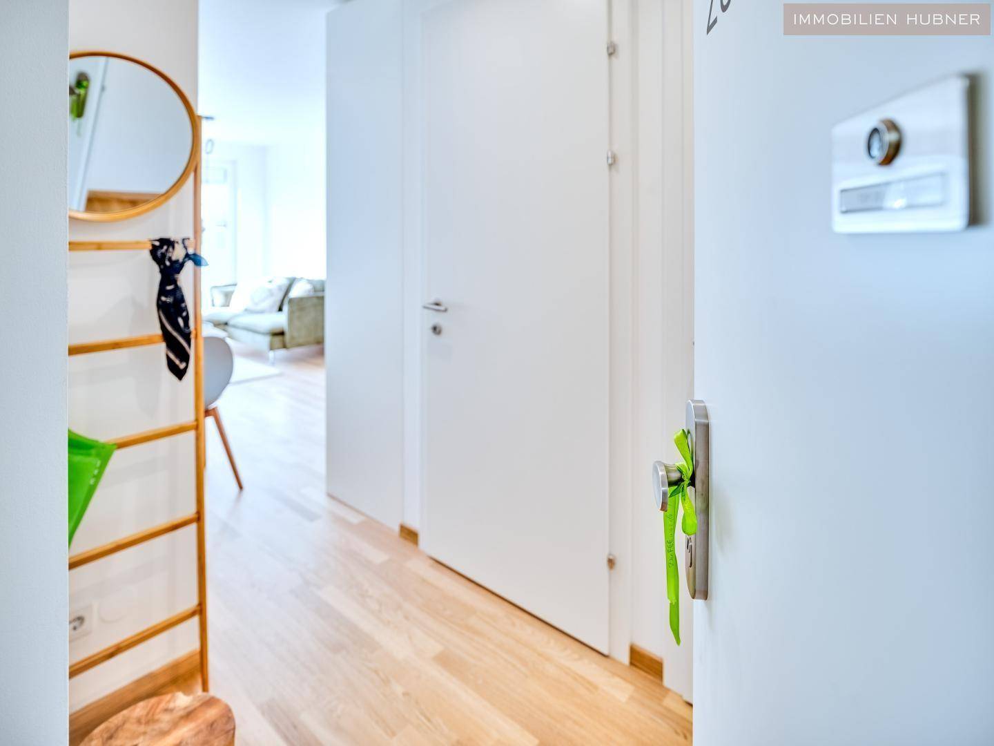 Heller Eingangsbereich mit Parkettboden und Garderobe, der in den Wohnbereich führt.