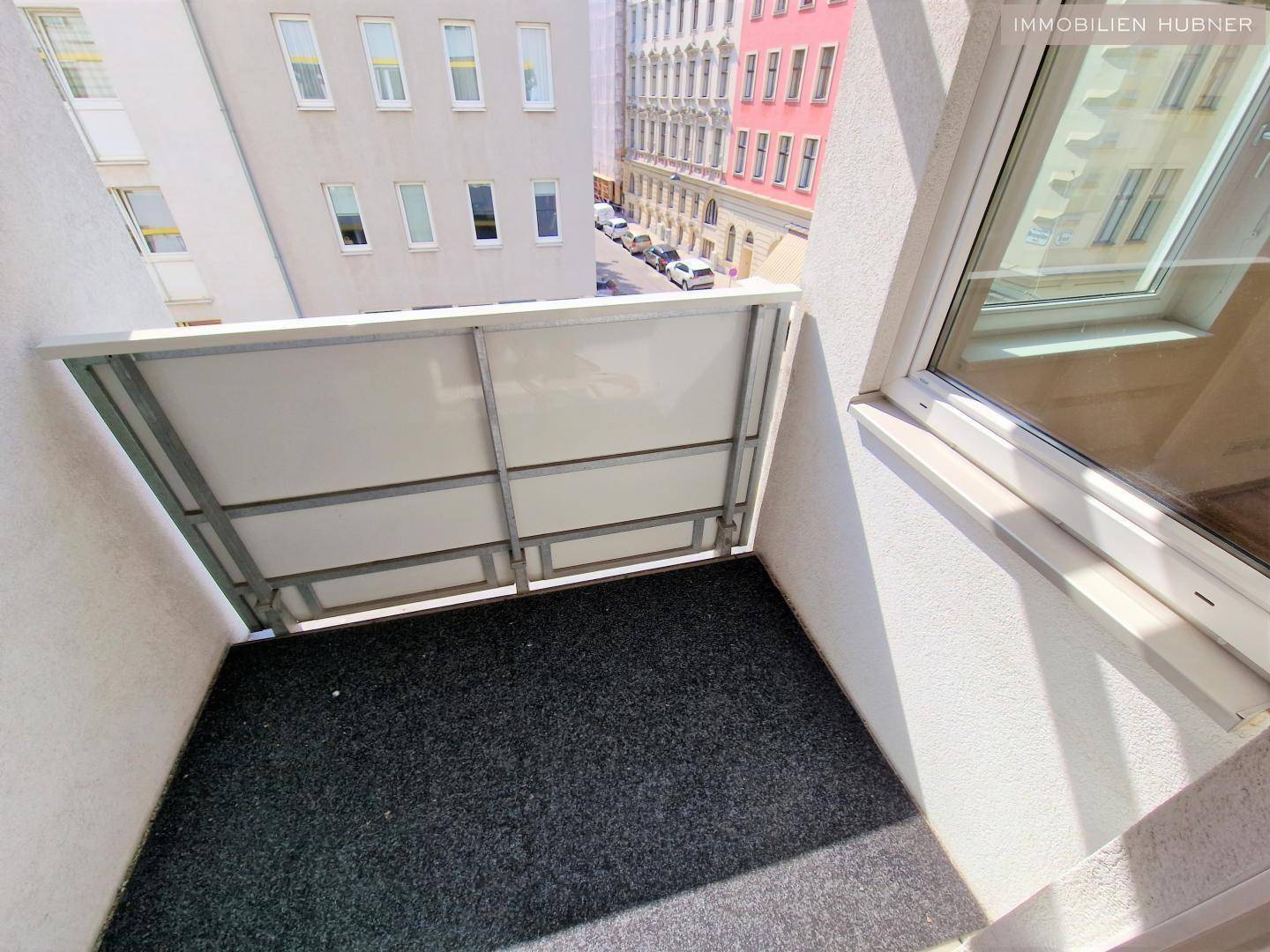 Kleiner Balkon mit Blick auf die umliegenden Gebäude und die Straße.