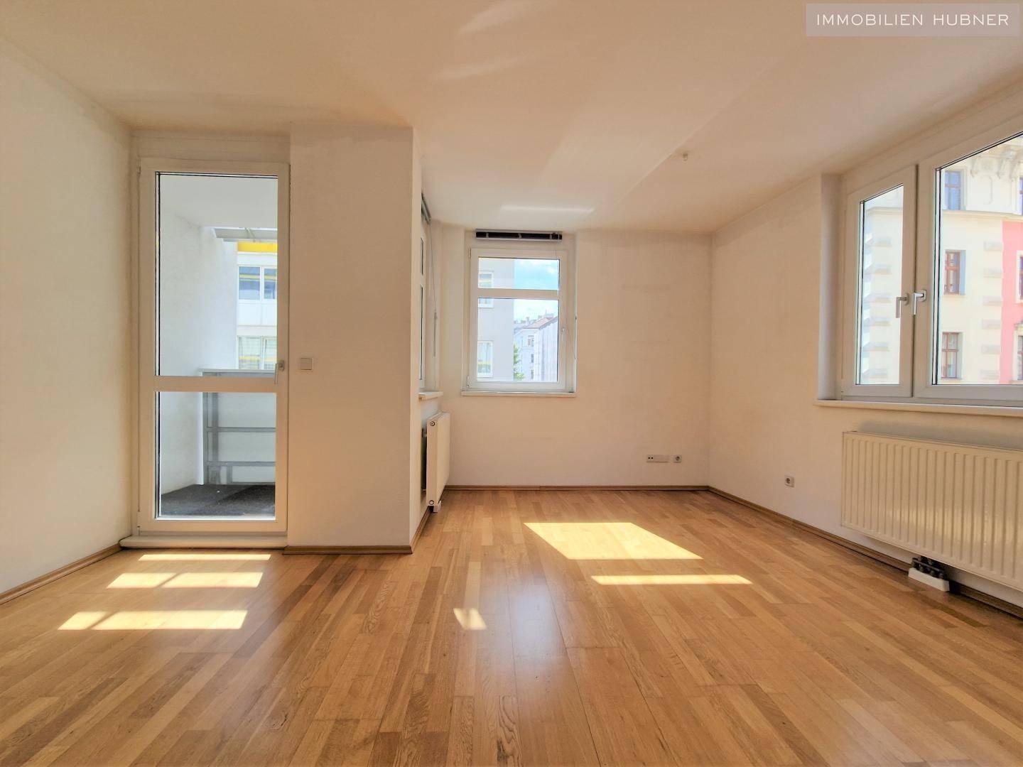 Geräumiges Zimmer mit Holzboden und viel Tageslicht, bereit zur individuellen Gestaltung.