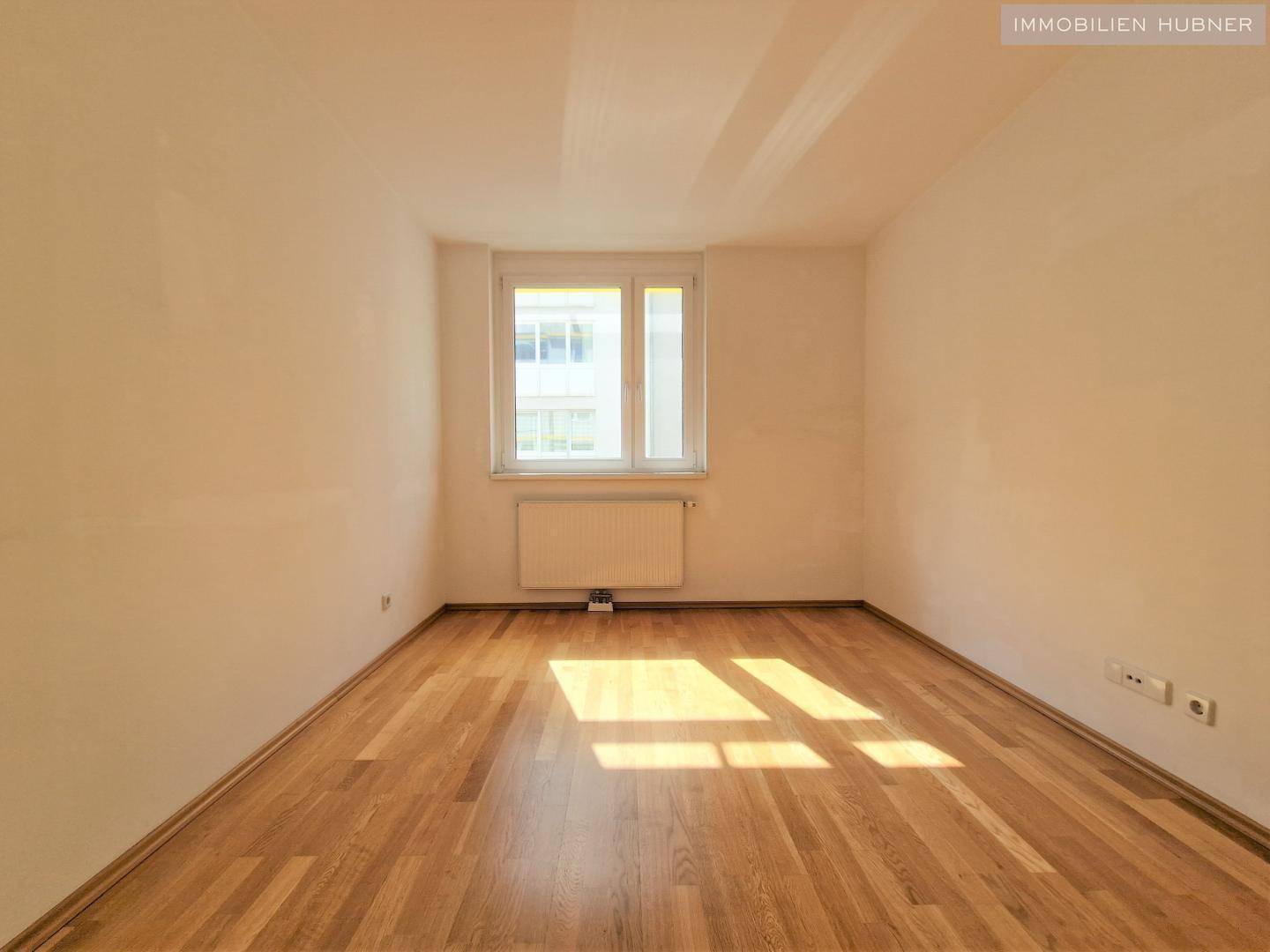 Helles Schlafzimmer mit Holzboden und Fenster, ideal für erholsame Nächte.