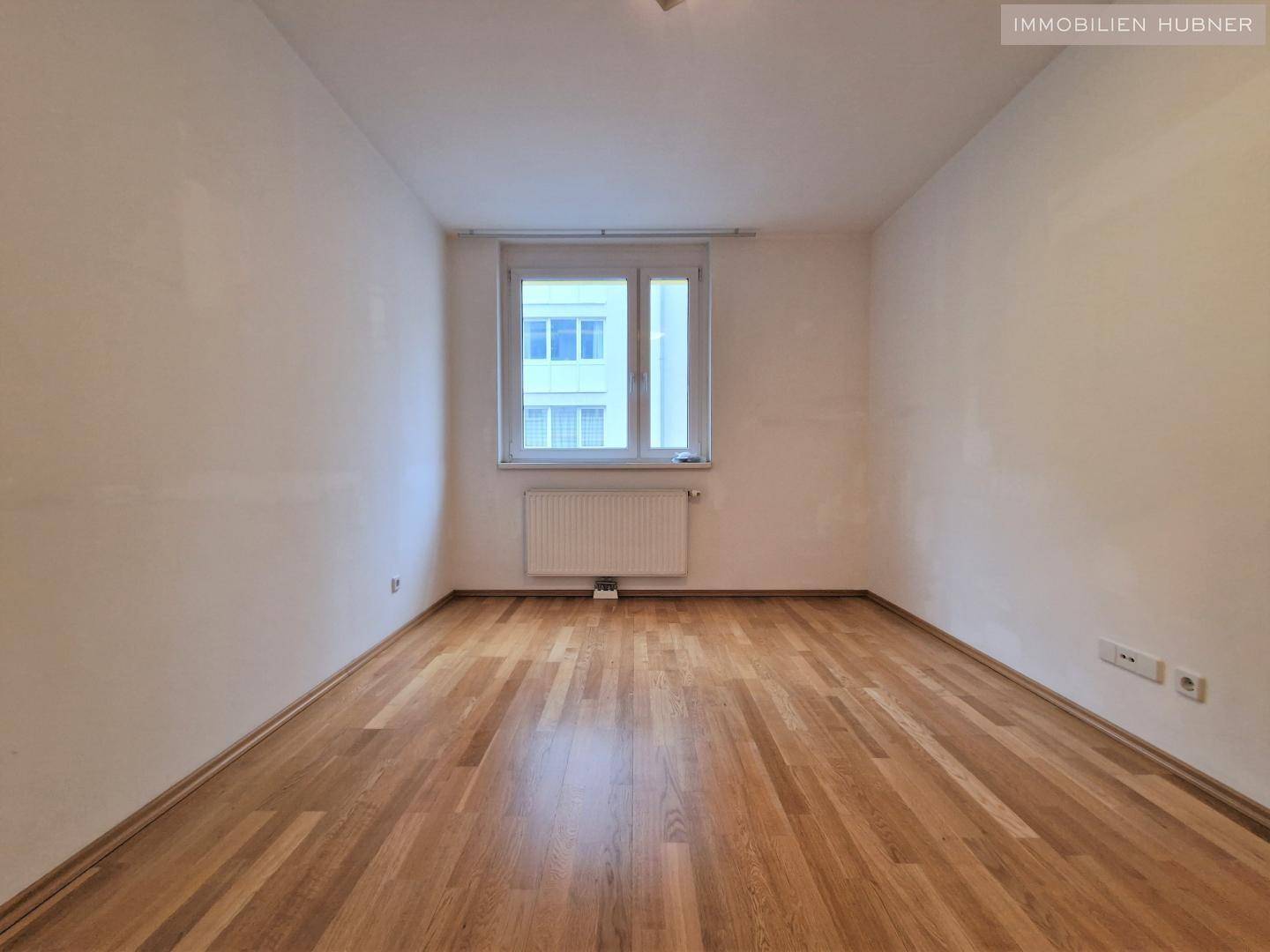 Ruhiges Schlafzimmer mit Parkettboden und Fenster, bietet Platz für individuelle Einrichtung.