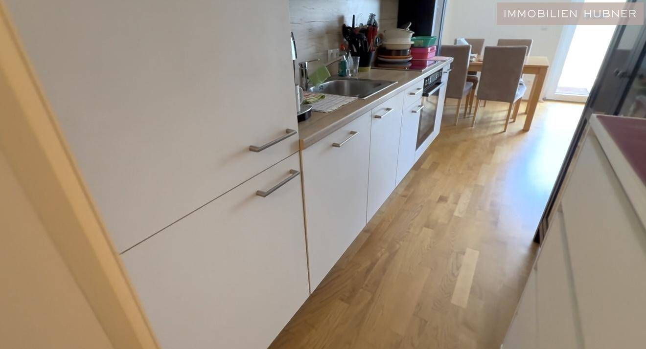 Kleine, moderne Küchenzeile mit weißen Schränken und Holzboden.