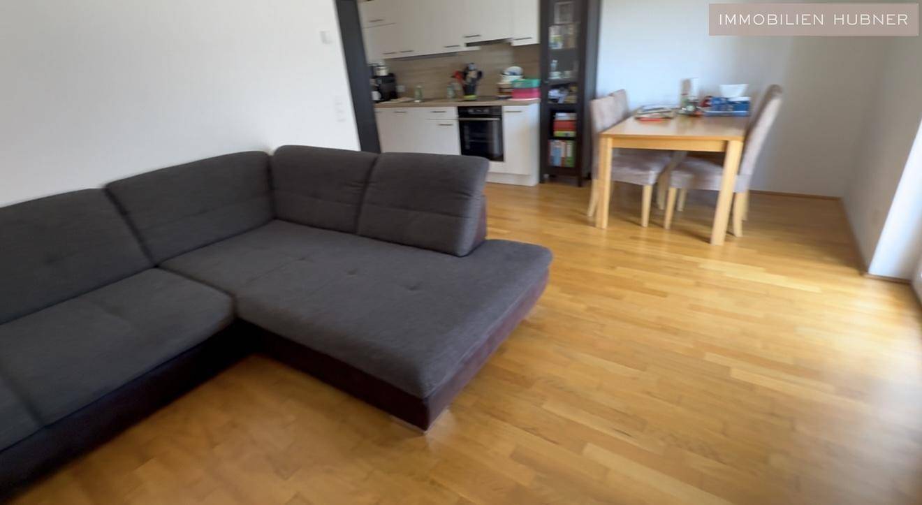Offener Wohnbereich mit Sofa, Esstisch und Blick auf die integrierte Küche.