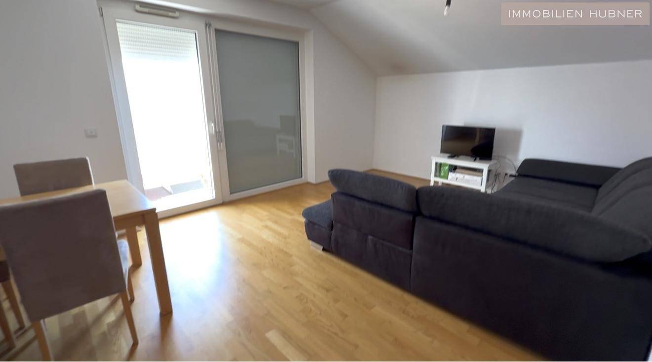 Heller Wohn- und Essbereich mit Holzboden und Zugang zum Balkon.