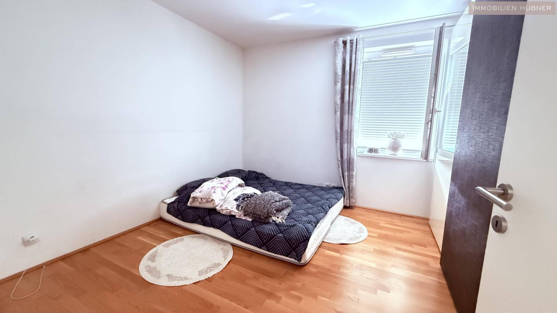 Gemütliches Schlafzimmer mit Holzboden und Fenster, ideal als Kinder- oder Gästezimmer.