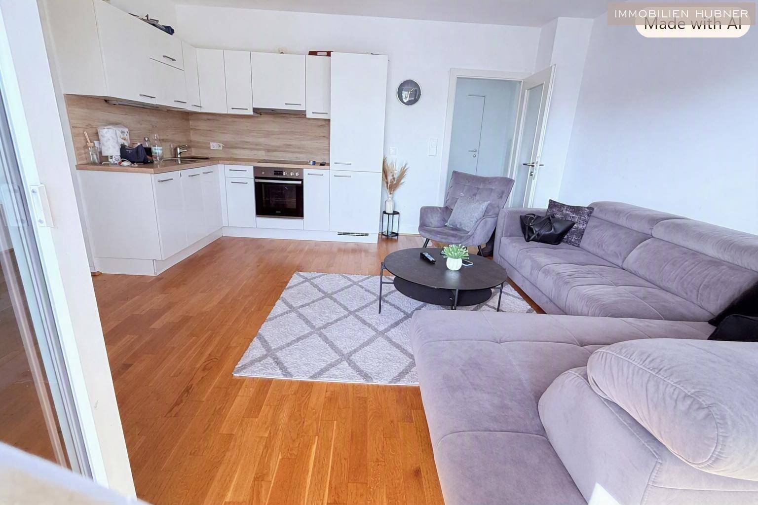 Heller offener Wohnbereich mit integrierter Küche, Holzfußboden und gemütlichem Sofa.